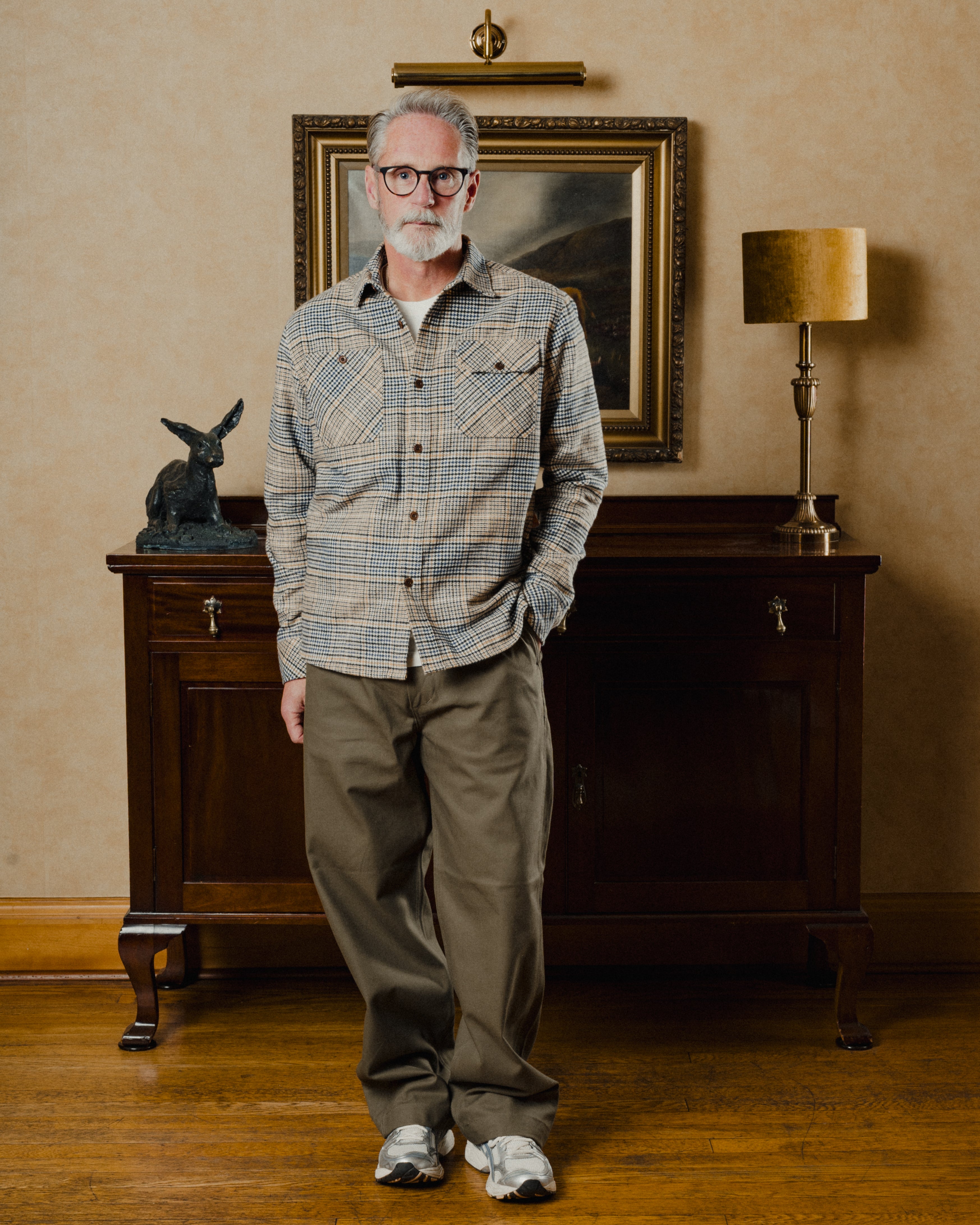 Man standing in a room with a painting and lamp in the background