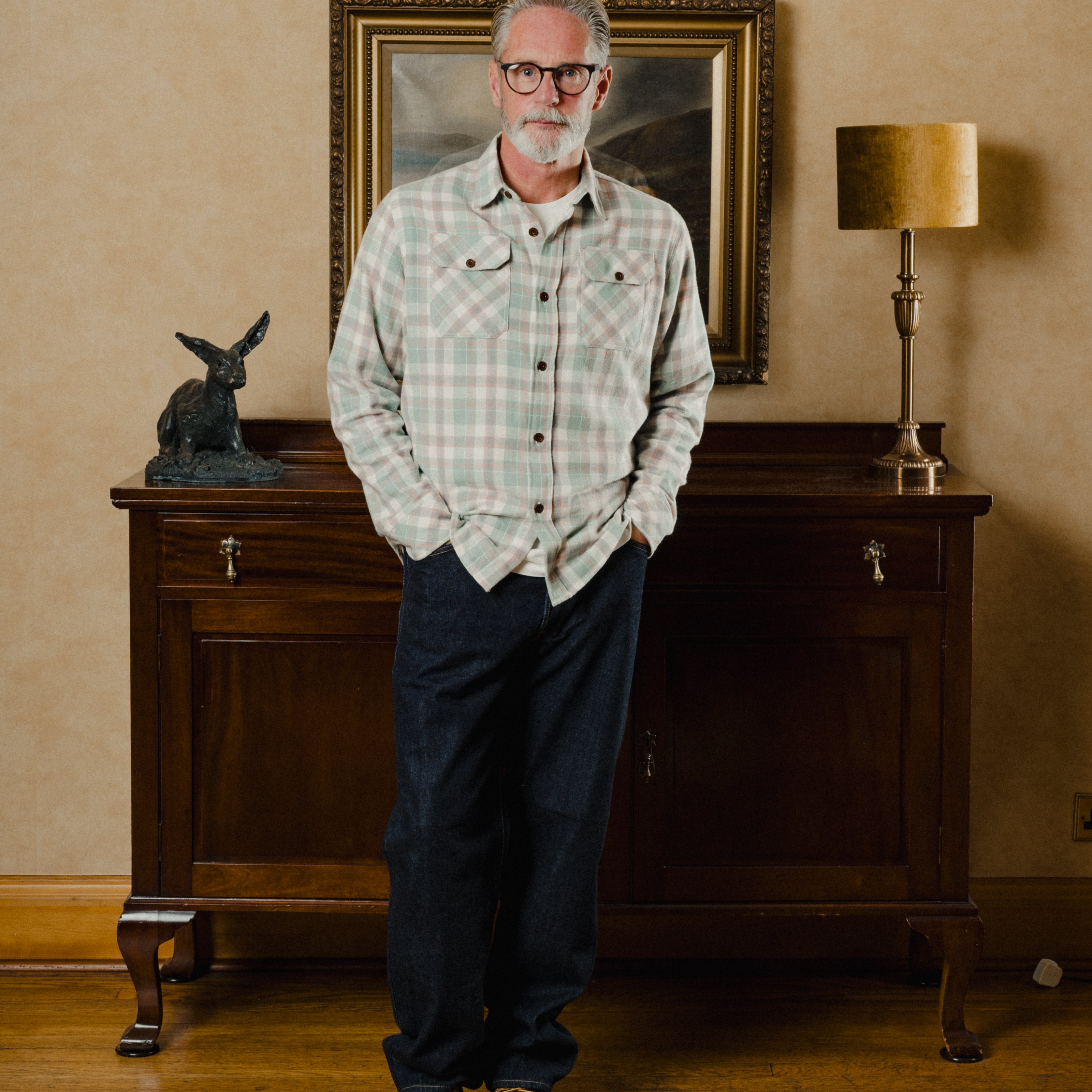 Man standing in a room with wooden furniture and decorative items