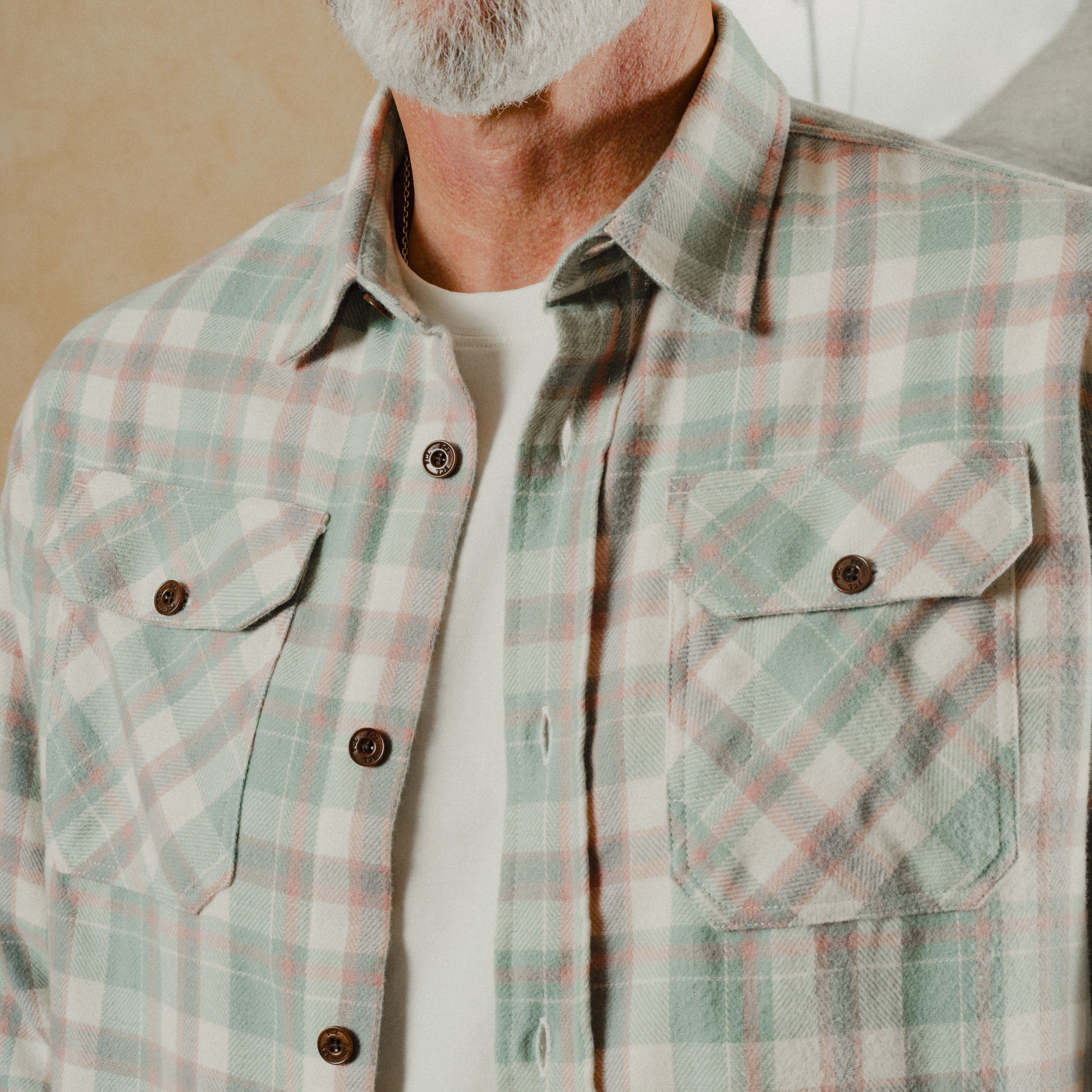 Man wearing a plaid shirt with a neutral background