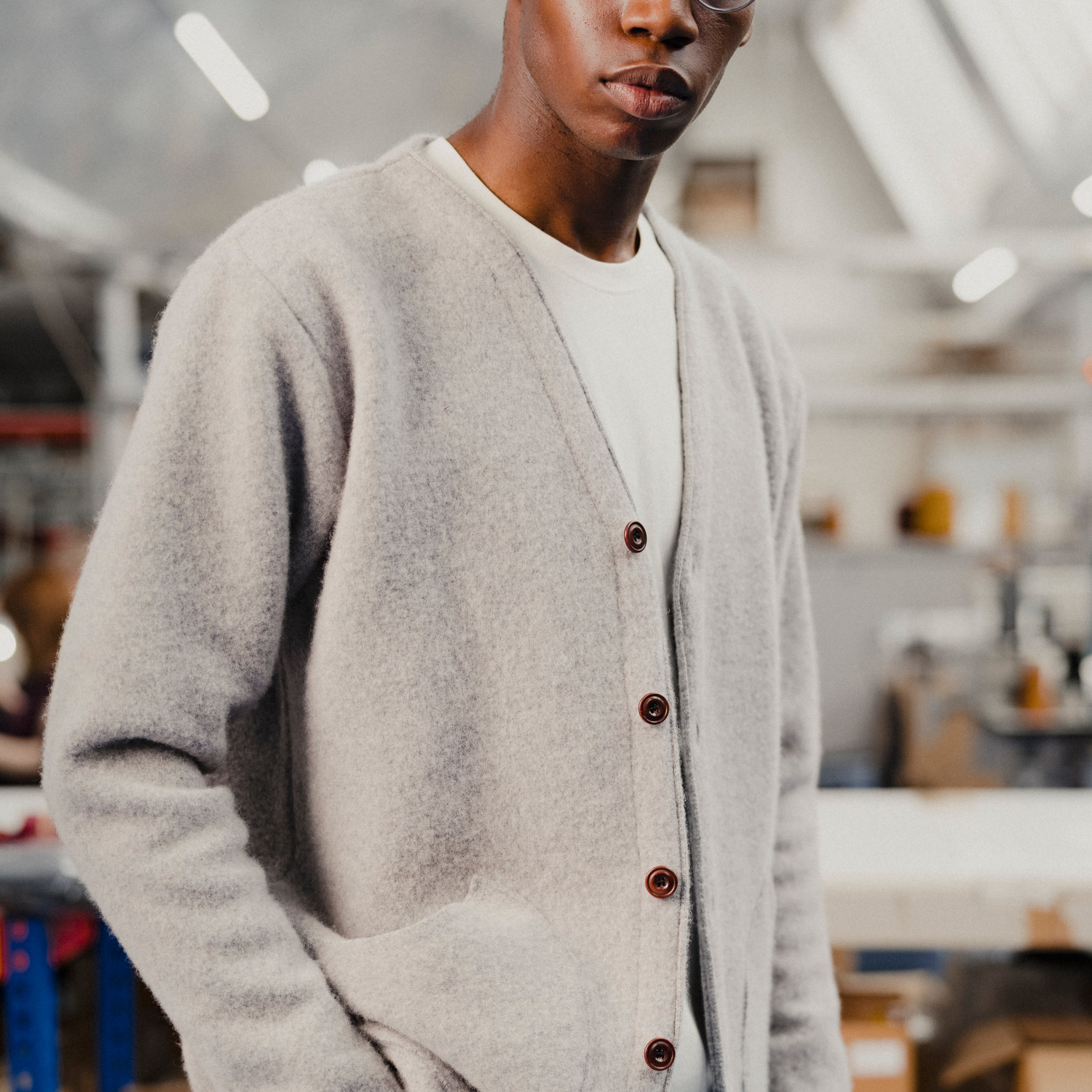 Person wearing a gray cardigan with brown buttons in an indoor setting