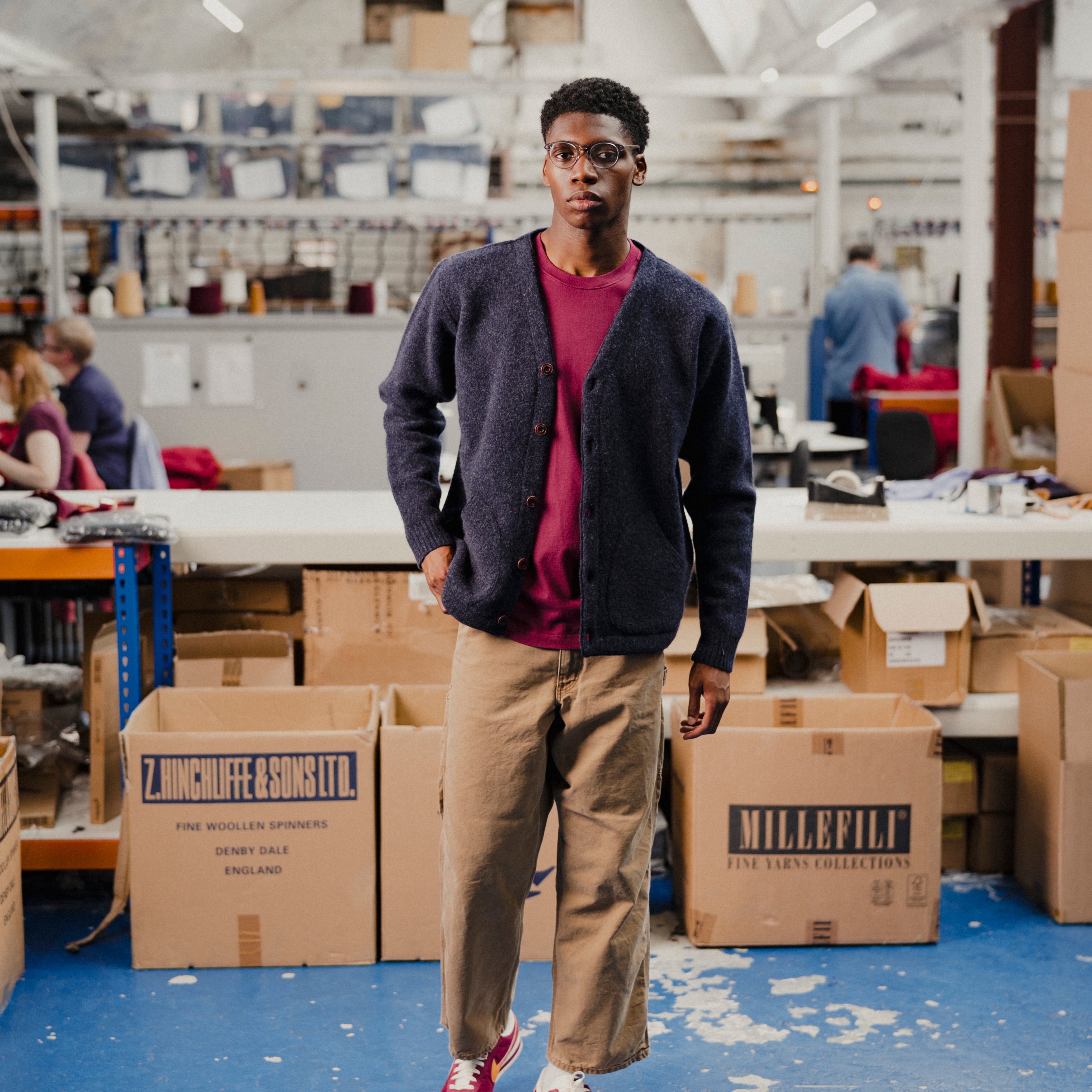 Man in a navy cardigan with a red t-shirt standing in fashion warehouse