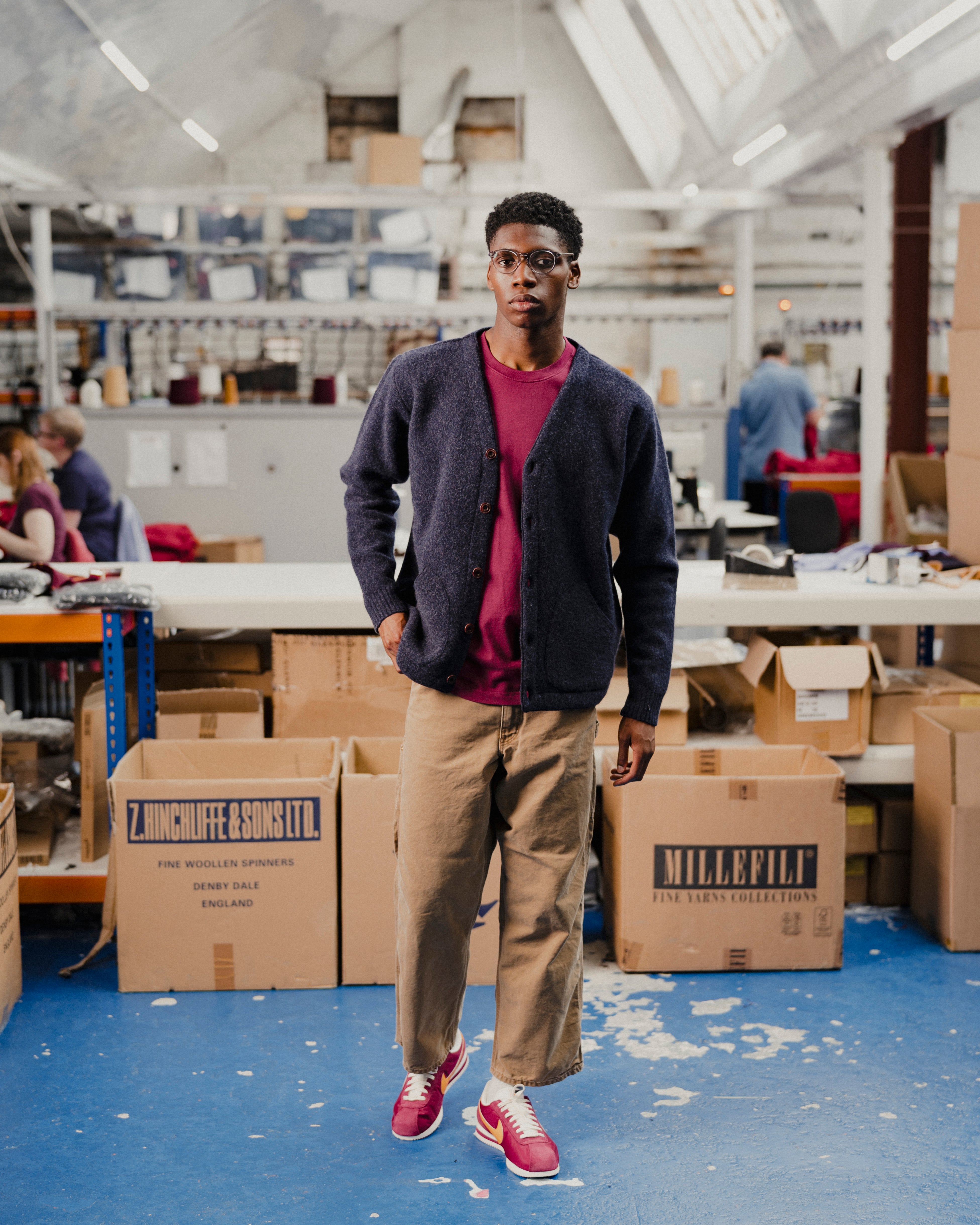 Man in a navy cardigan with a red t-shirt standing in fashion warehouse