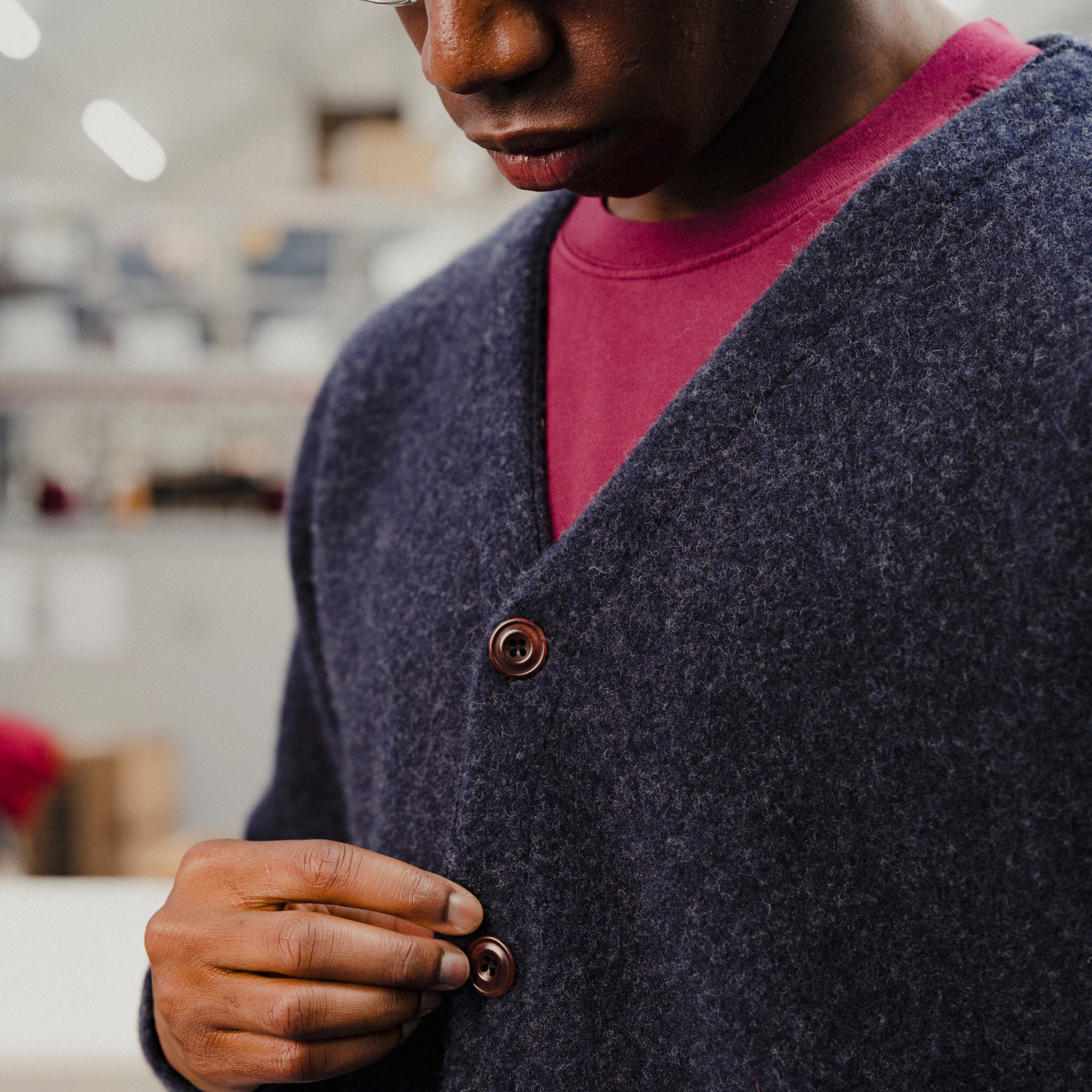 Person wearing a navy cardigan with a blurred indoor background