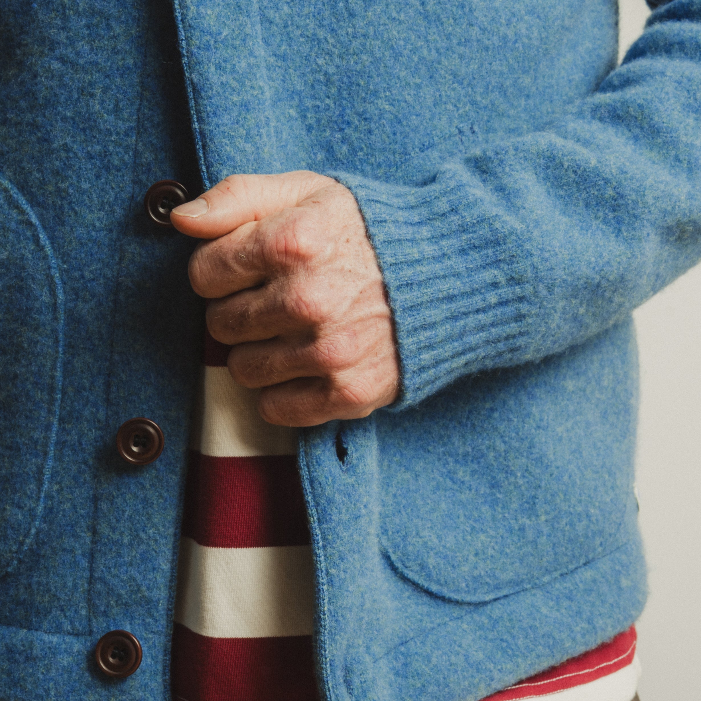 Close-up of a person wearing a blue jacket with a striped shirt underneath.