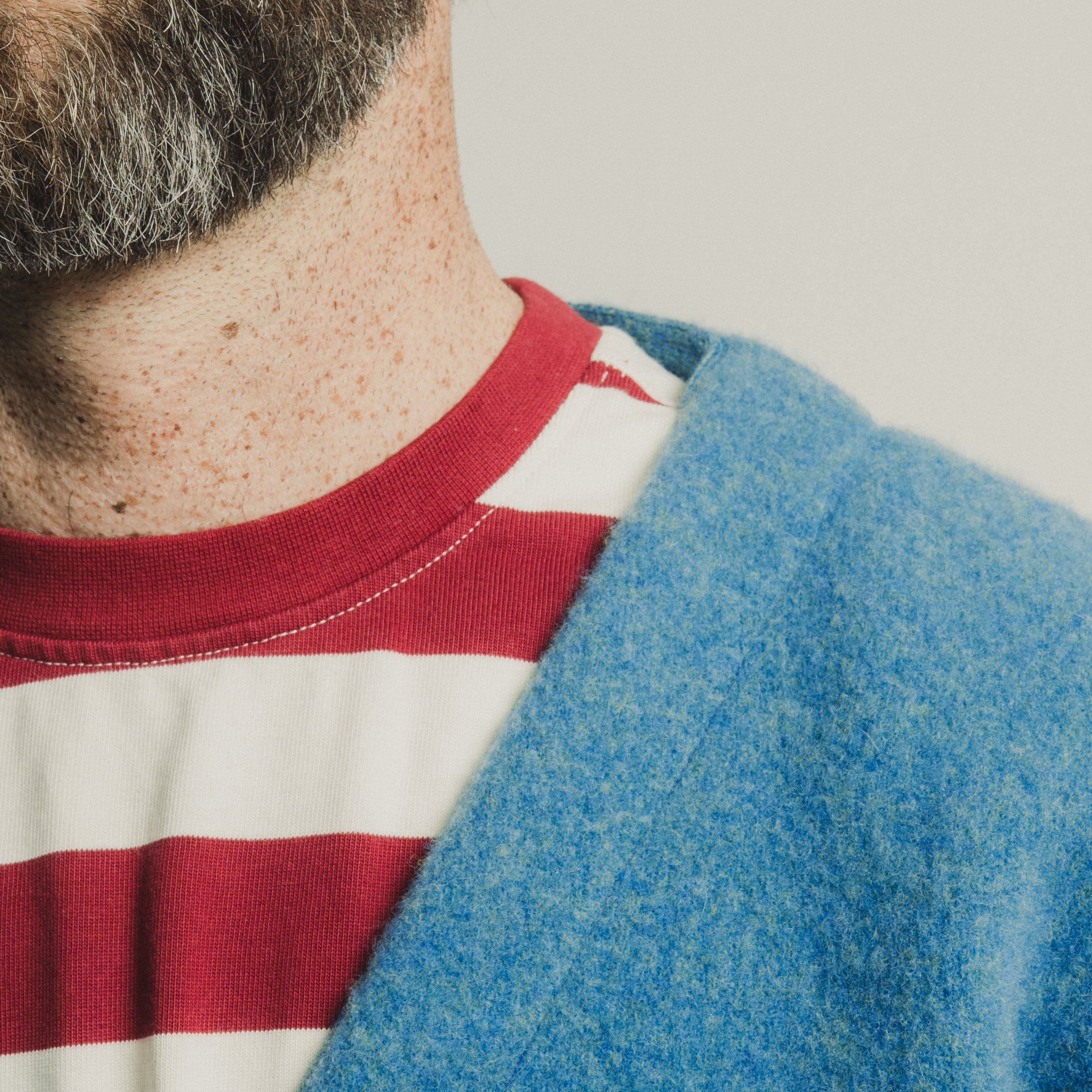 Person wearing a blue cardigan over a red and white striped shirt