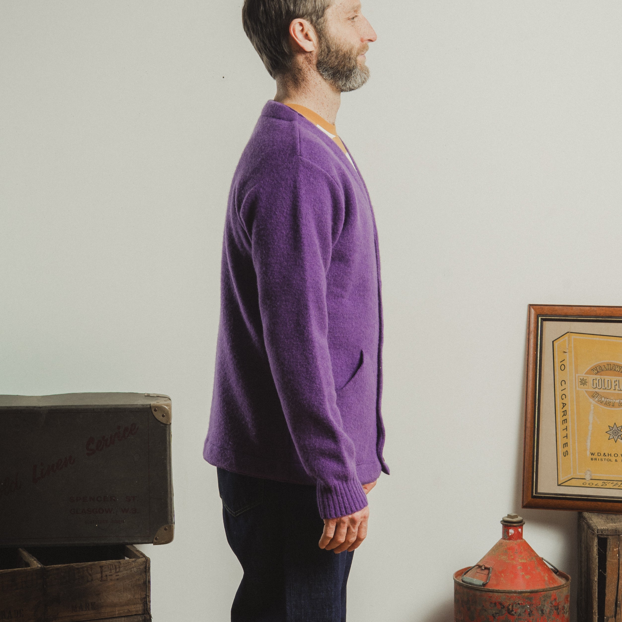 Man wearing a purple sweater standing in a room with vintage items.