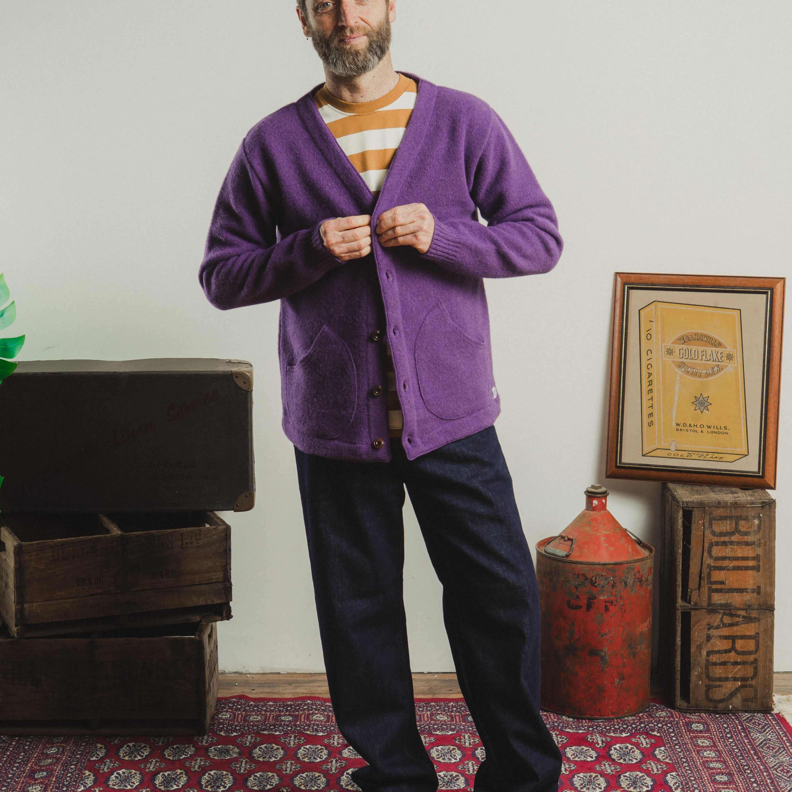 Man wearing a purple cardigan in a room with vintage furniture and decor.