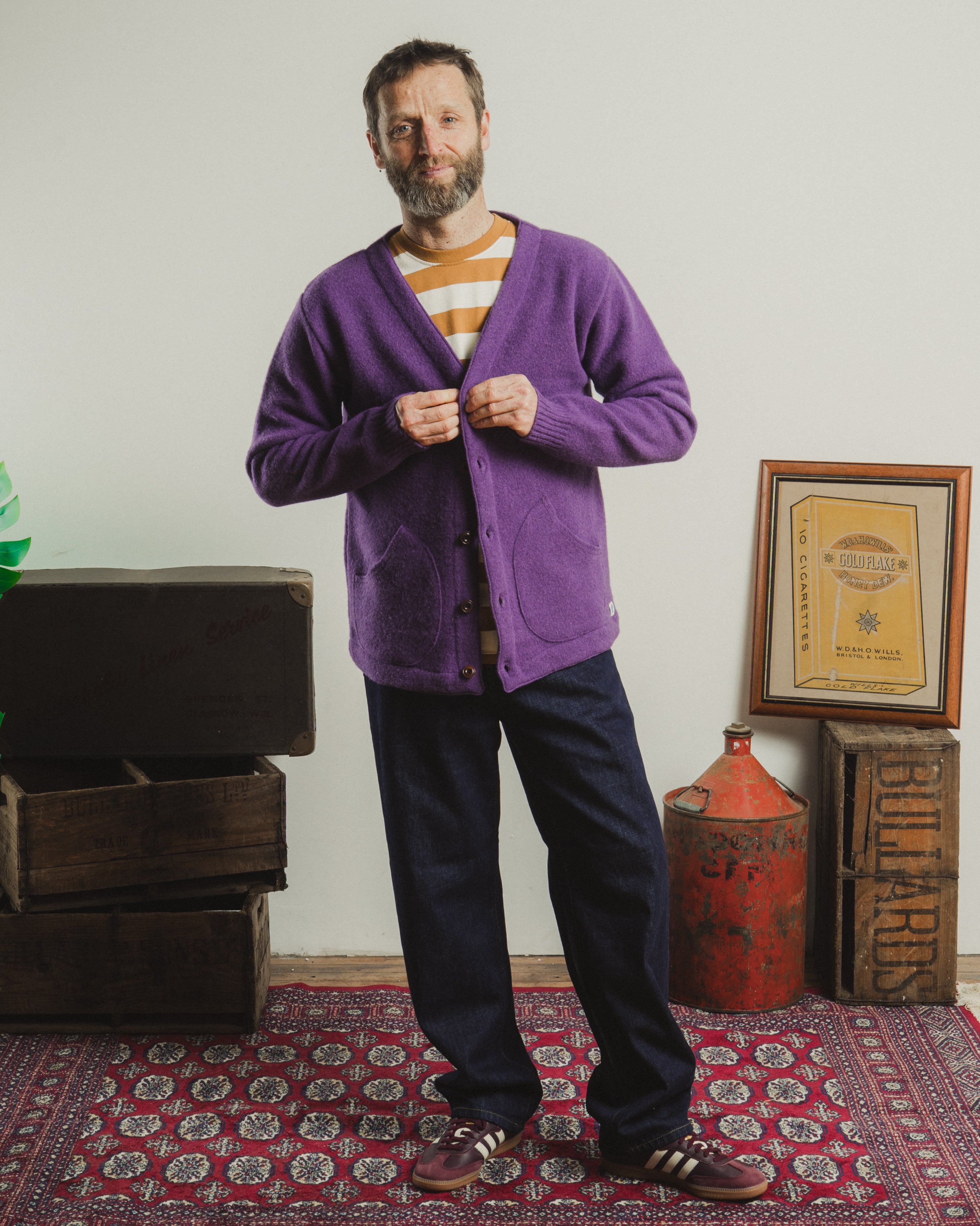 Man wearing a purple cardigan in a room with vintage furniture and decor.