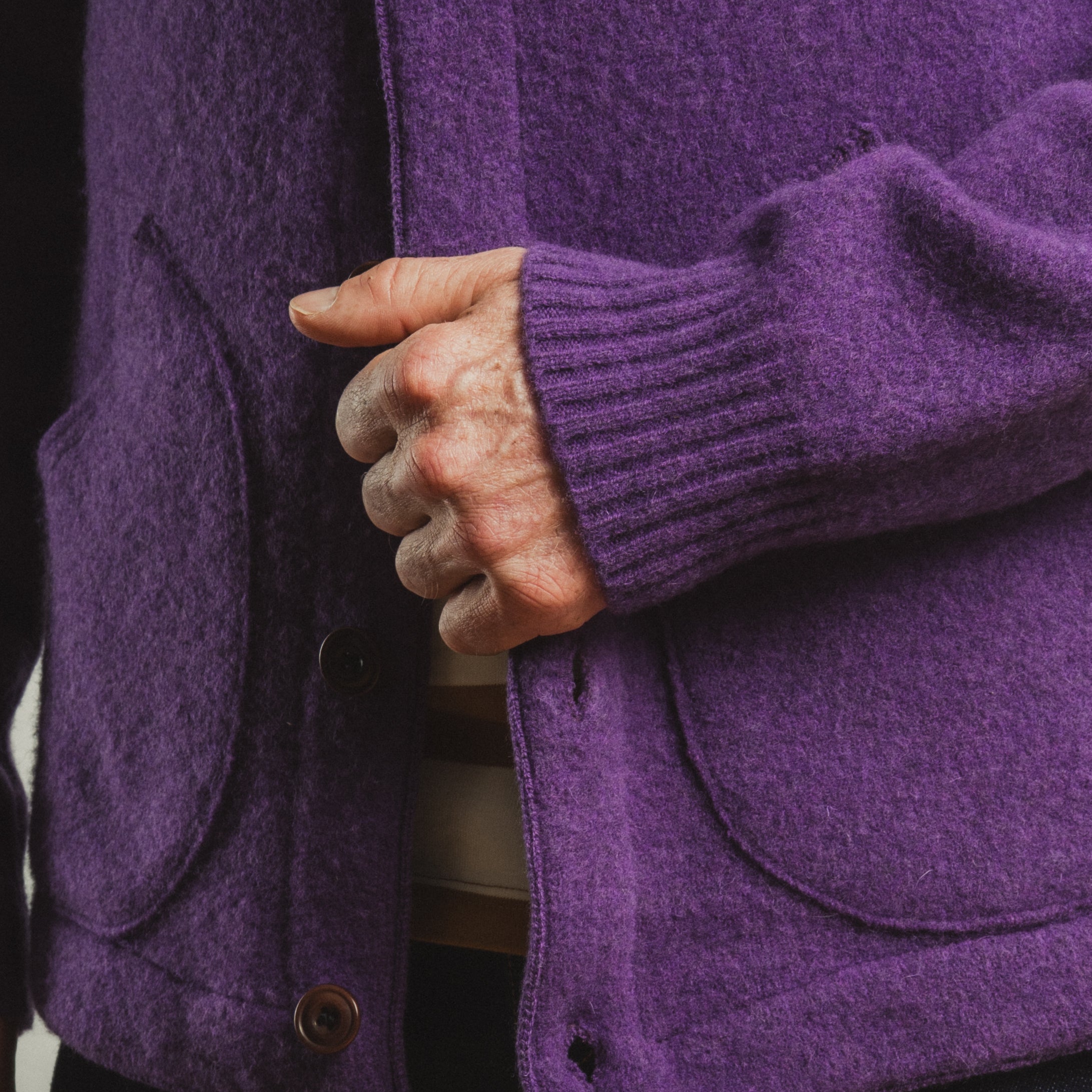 Close-up of a person wearing a purple coat with a buttoned pocket.