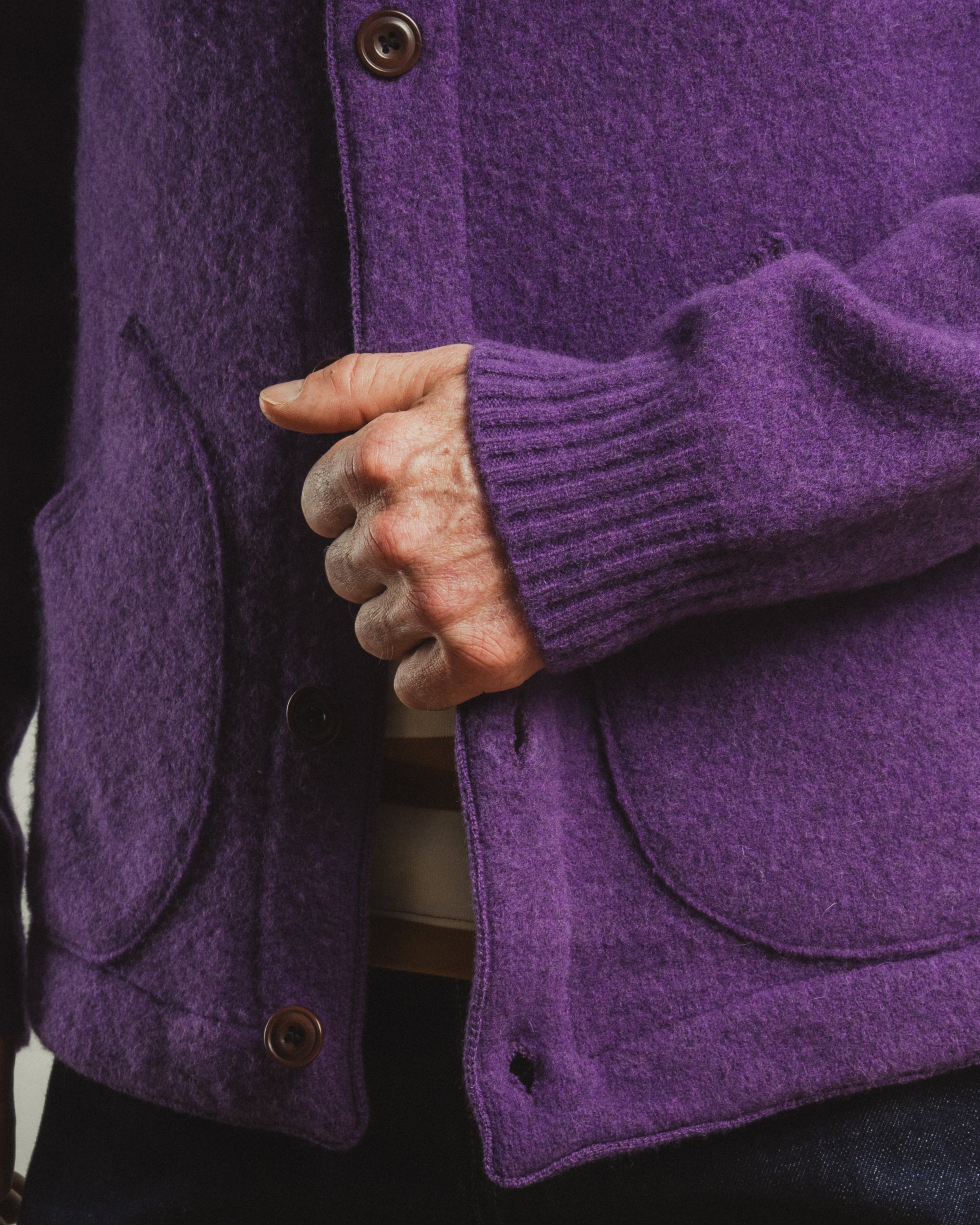 Close-up of a person wearing a purple coat with a buttoned pocket.