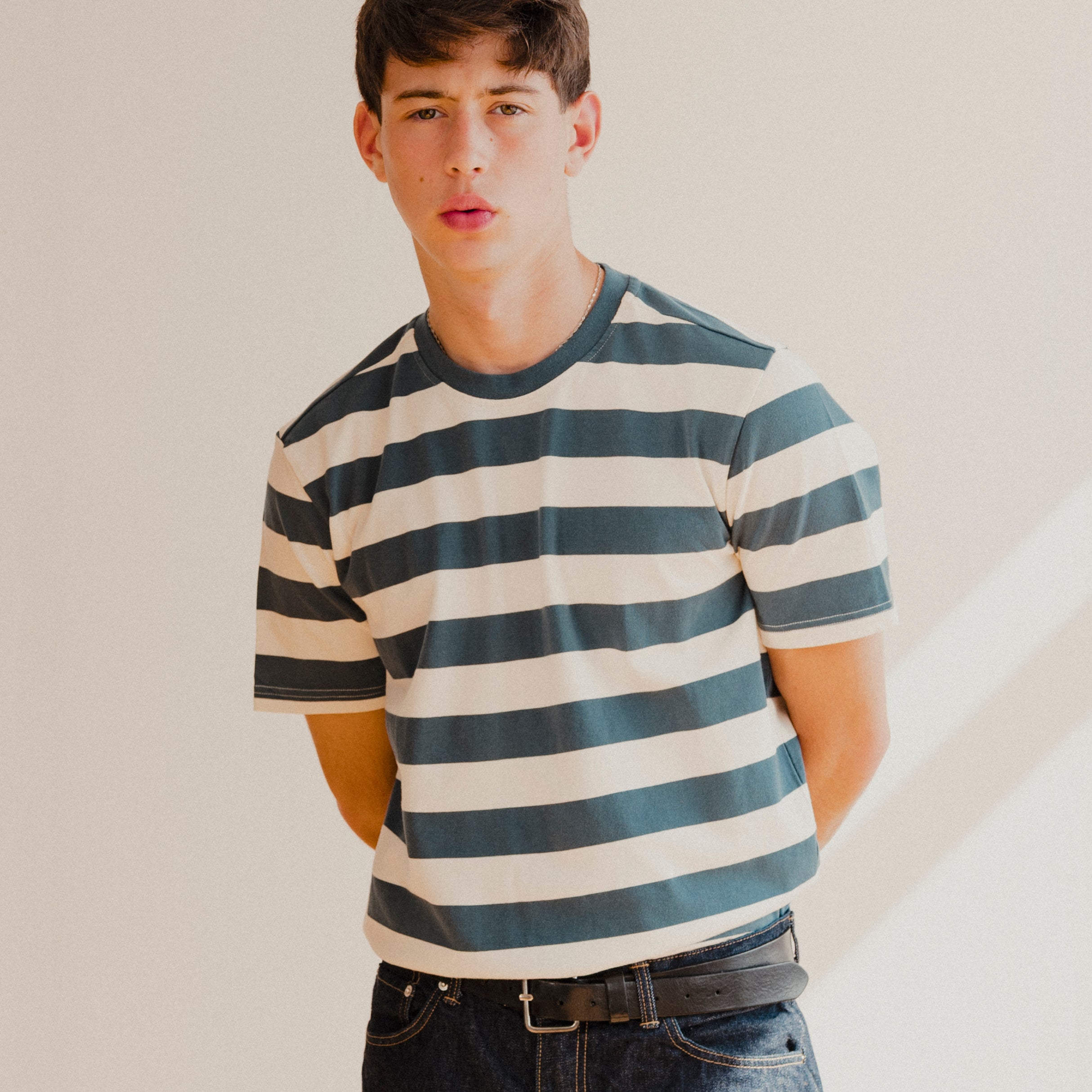 Person wearing a blue and white striped shirt and jeans against a plain background