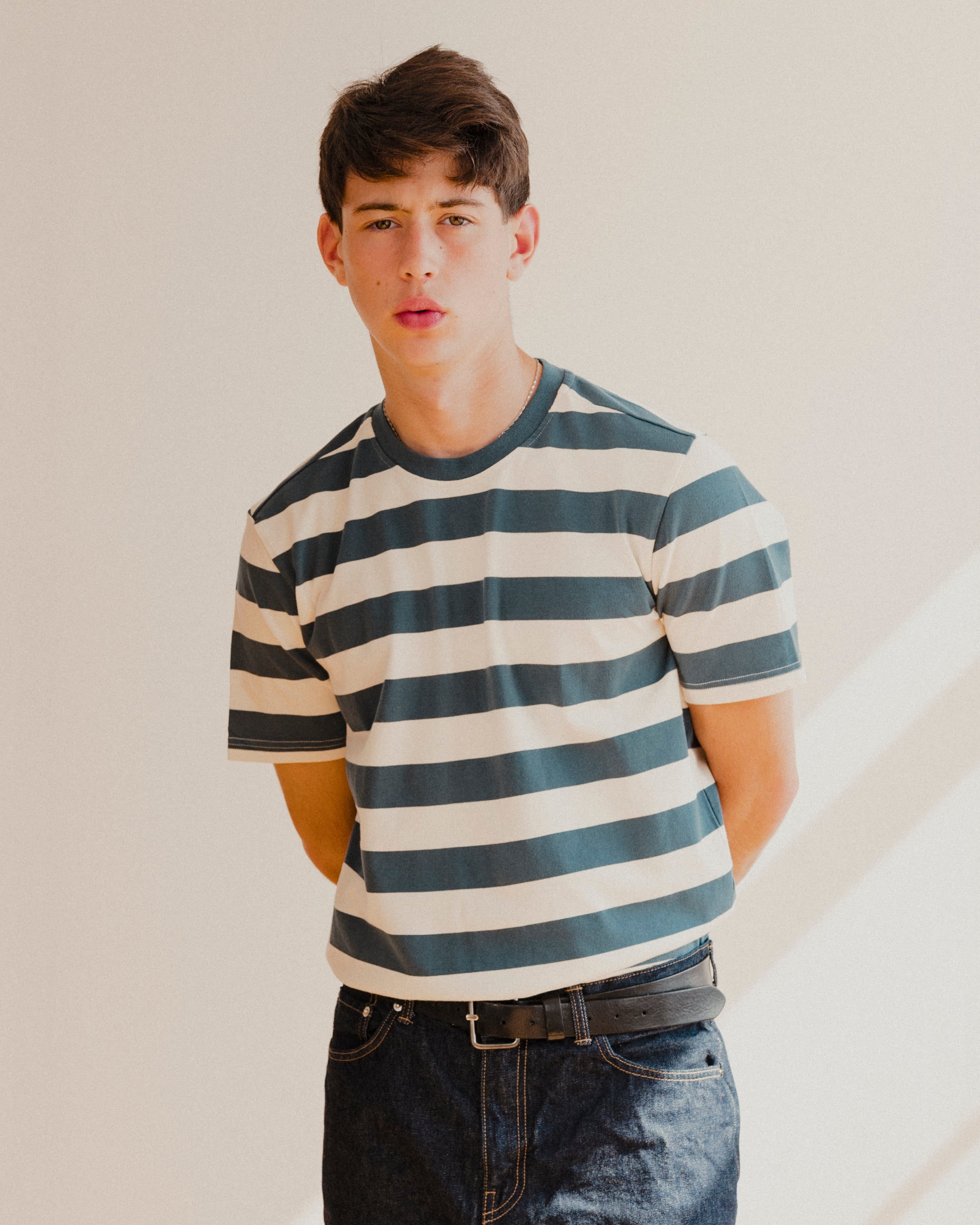 Person wearing a blue and white striped shirt and jeans against a plain background