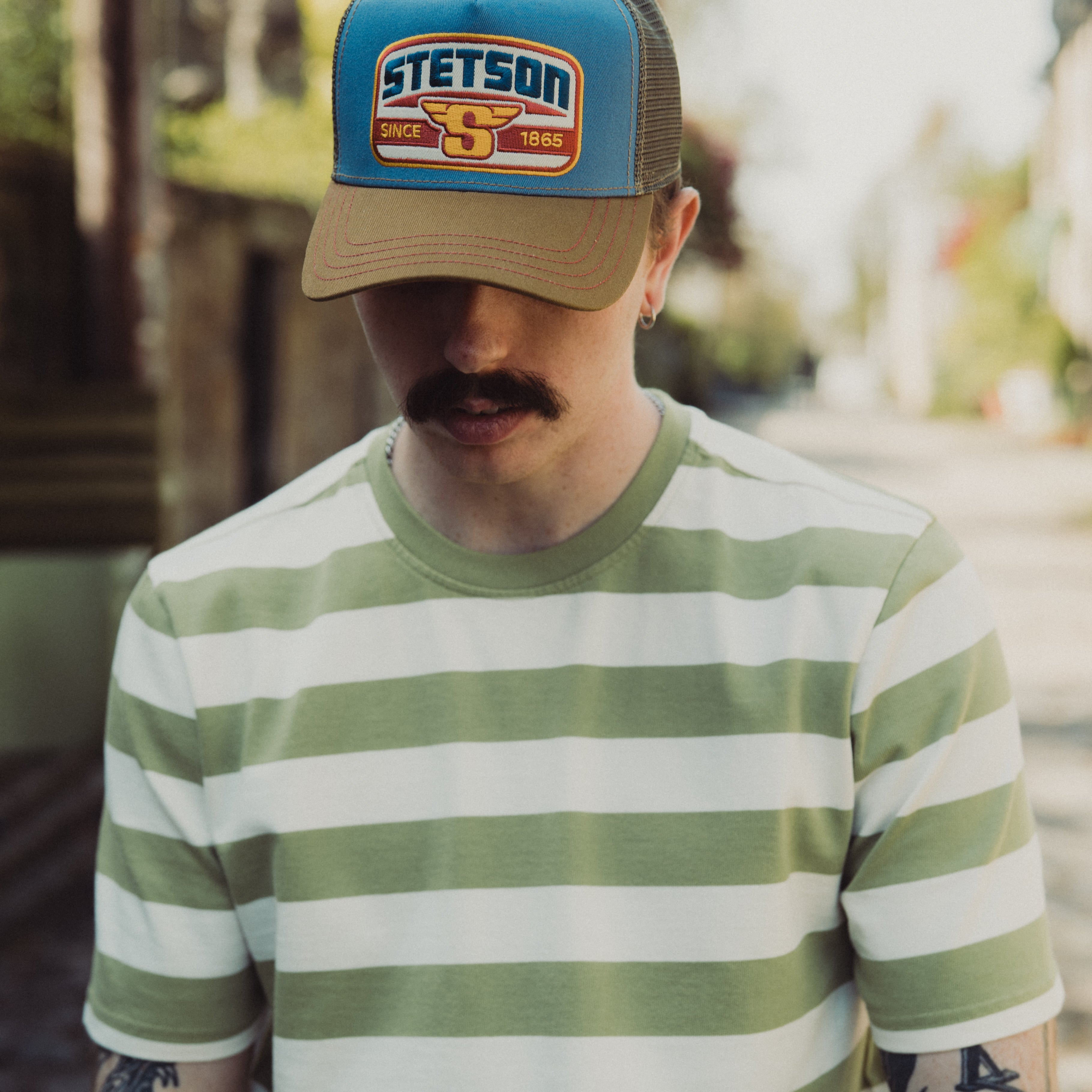 Man wearing a striped shirt and Stetson cap outdoors