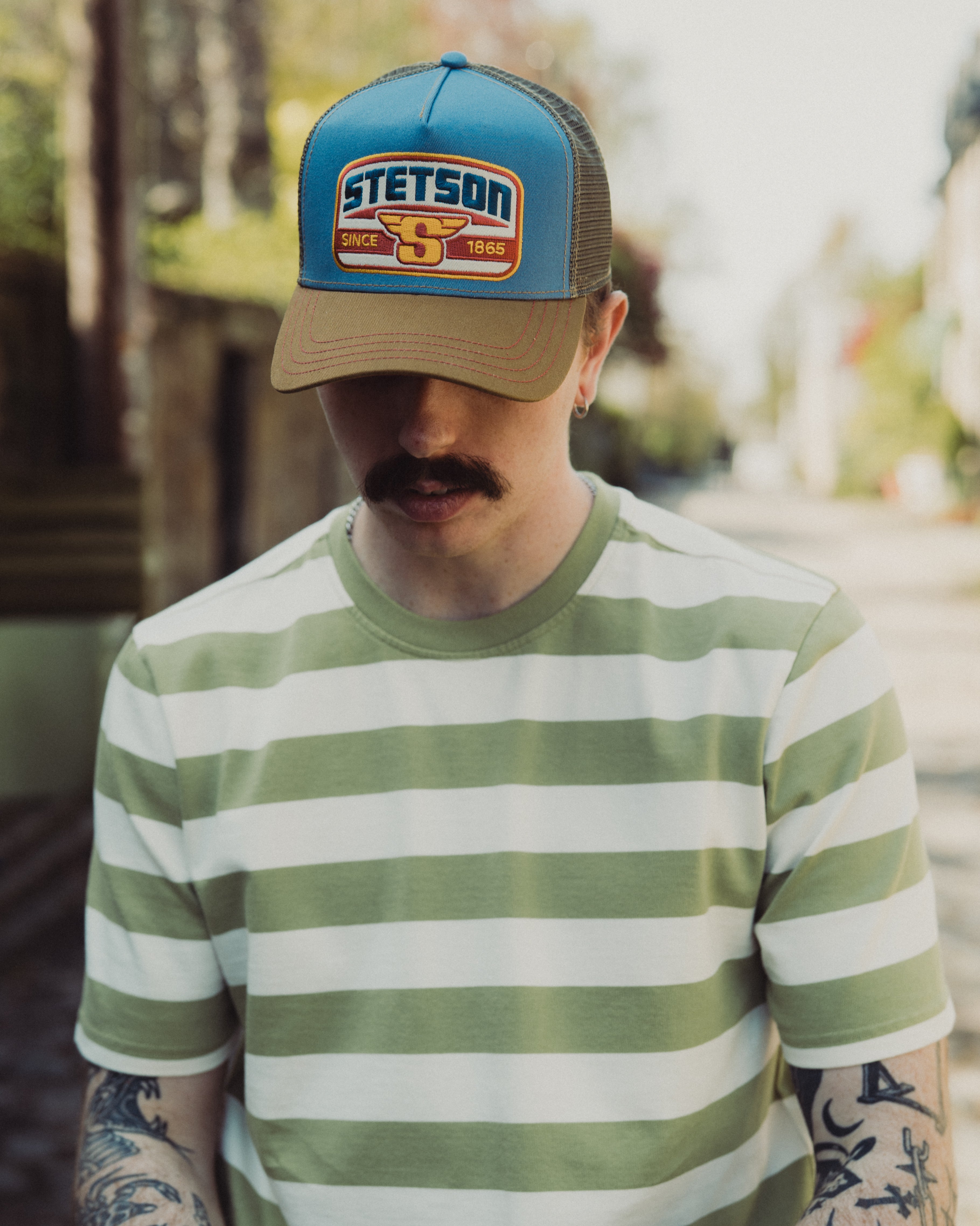 Man wearing a striped shirt and Stetson cap outdoors