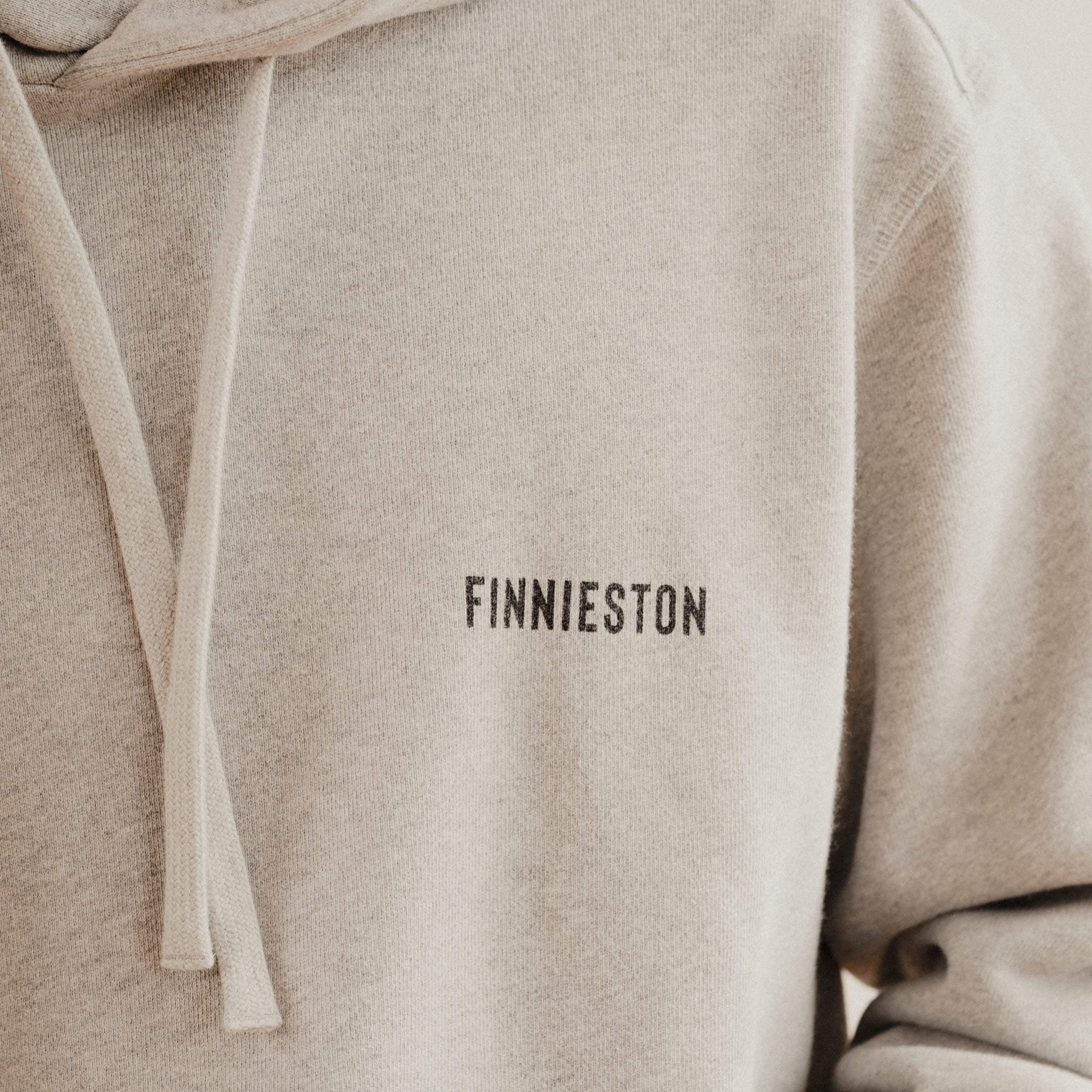 grey hoodie with 'FINNIESTON' text on a plain background