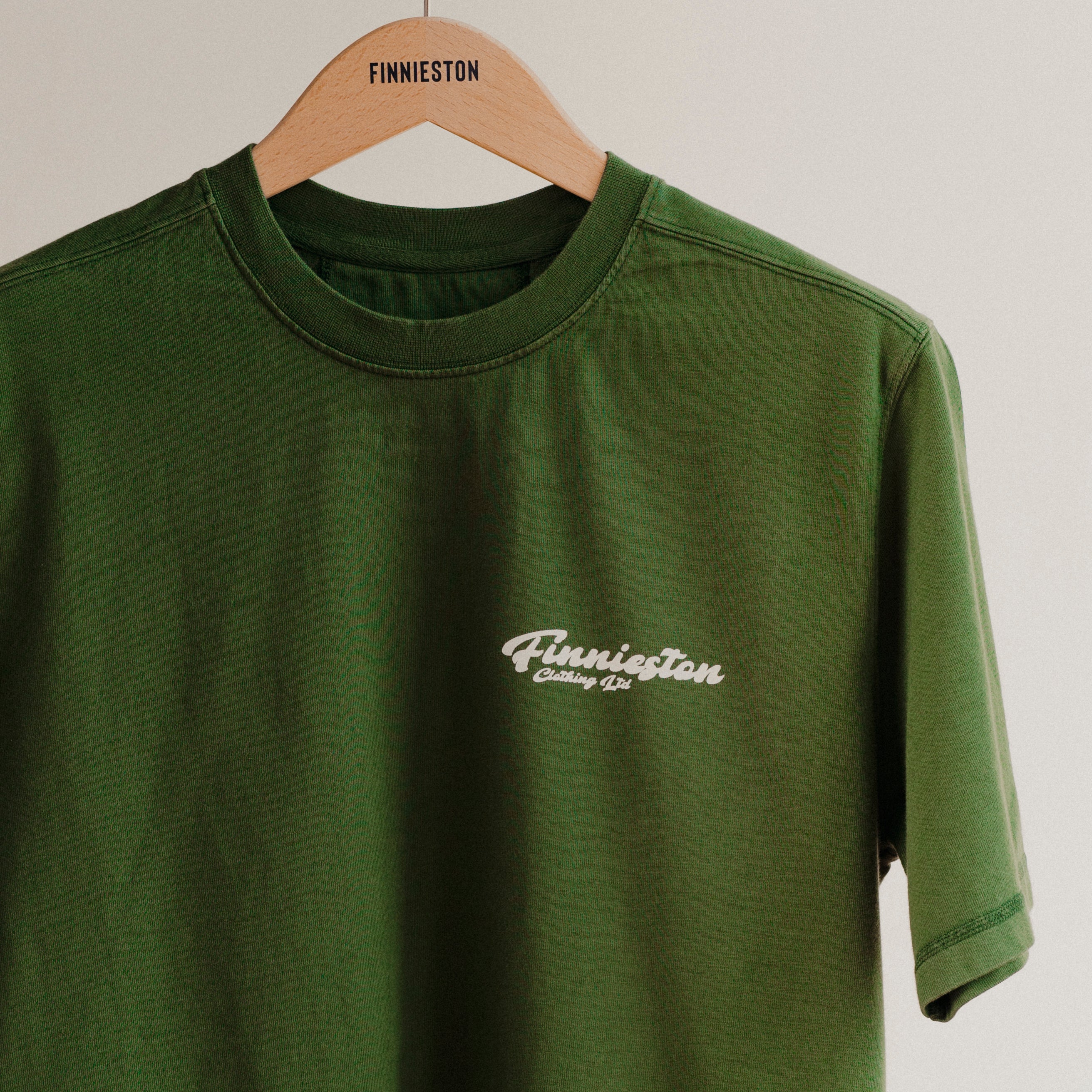 Green t-shirt with 'Finnieston' logo on a hanger against a white background