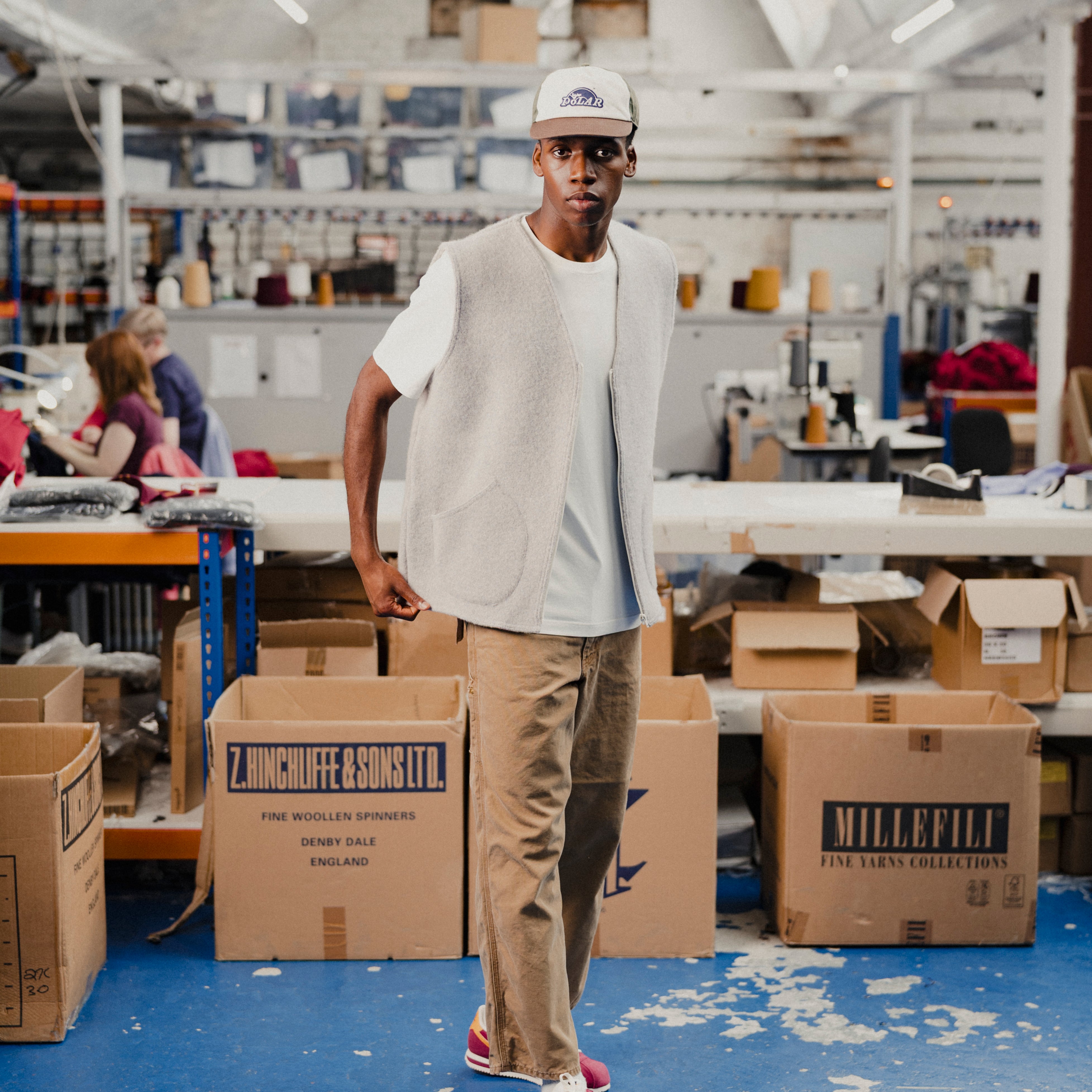 Man wearing a light grey vest and a white t-shirt in a warehouse setting