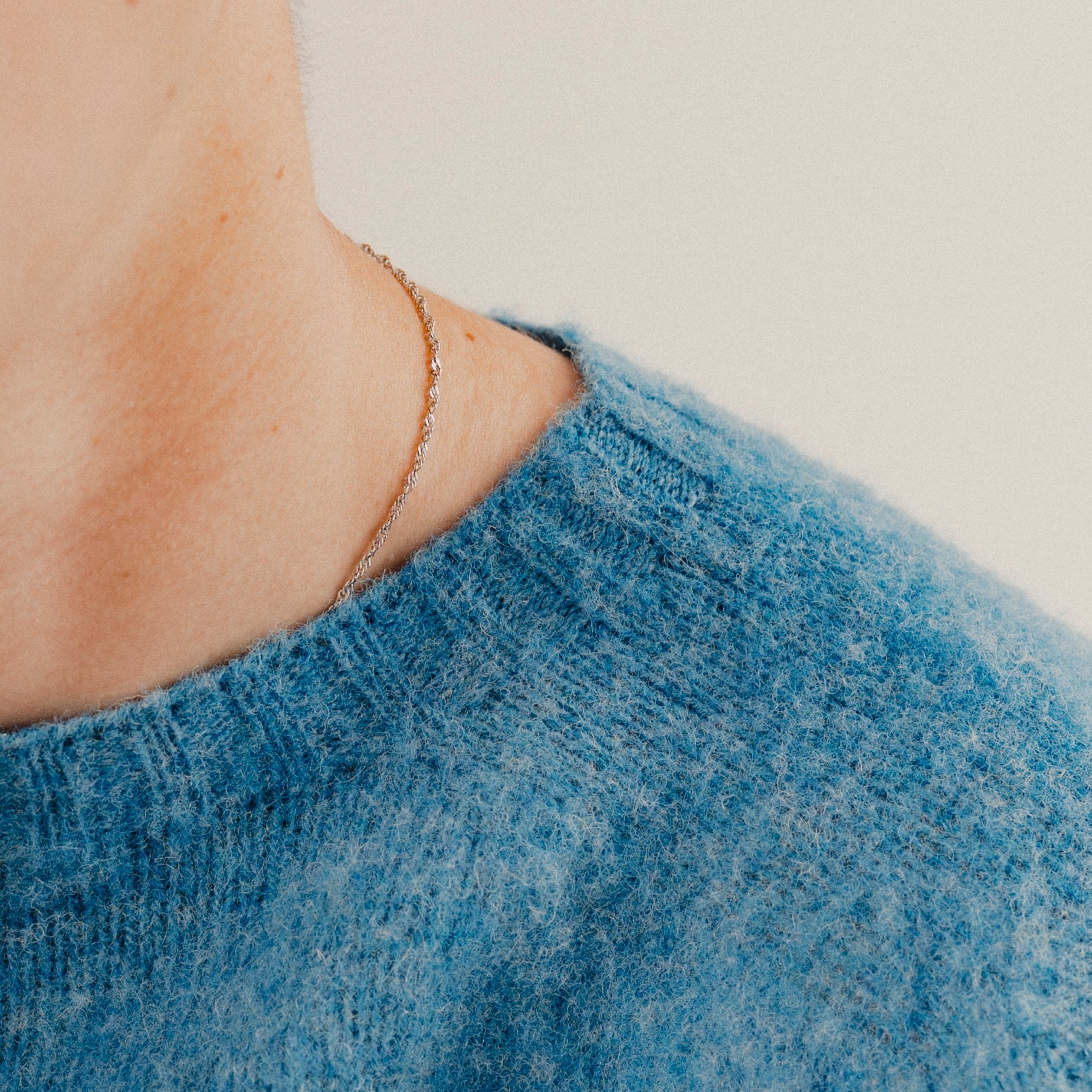 Close up on a blue wool knit crewneck sweatshirt jumper focused on the neckline with a plain background