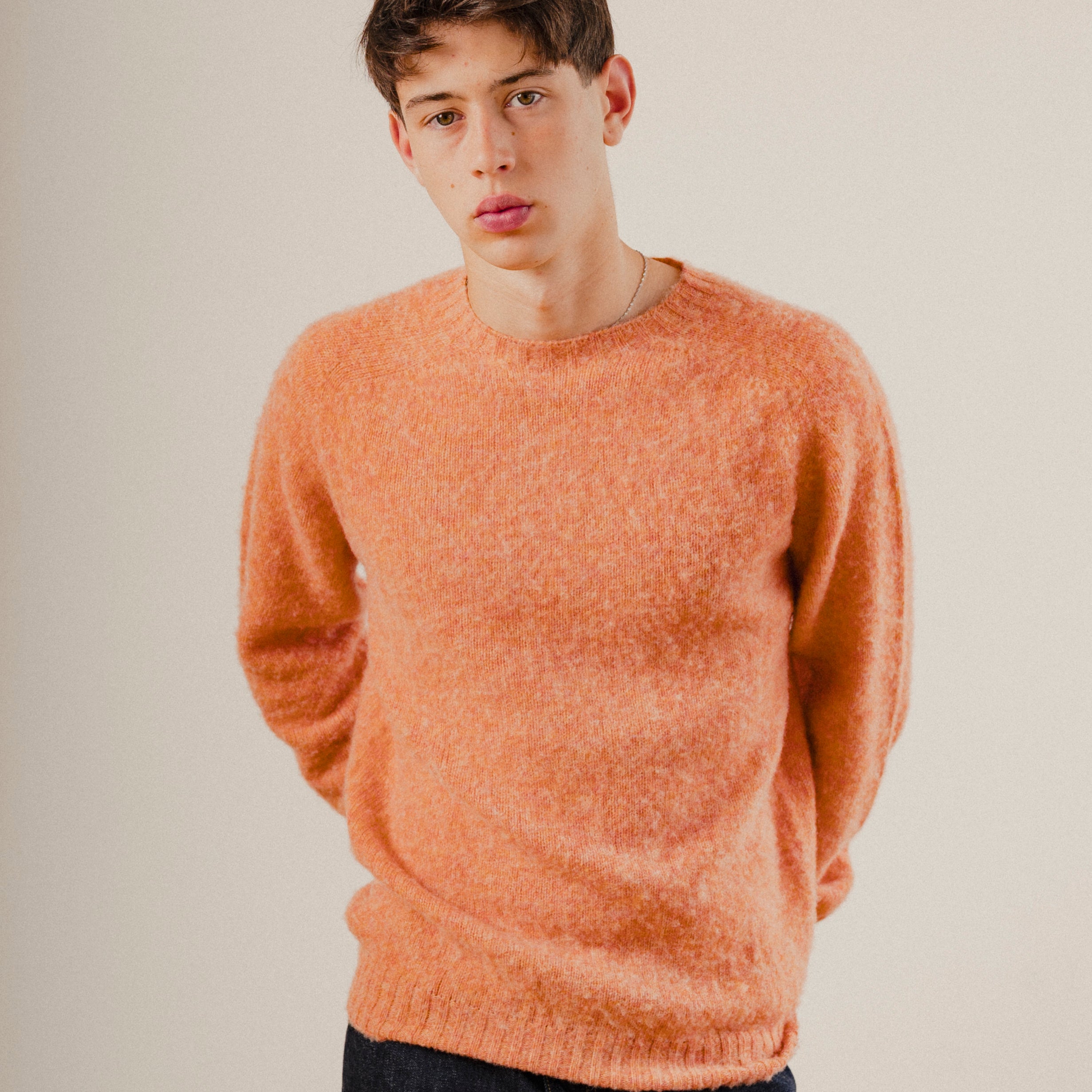 Man in an orange wool knit sweater crewneck jumper on a plain white background