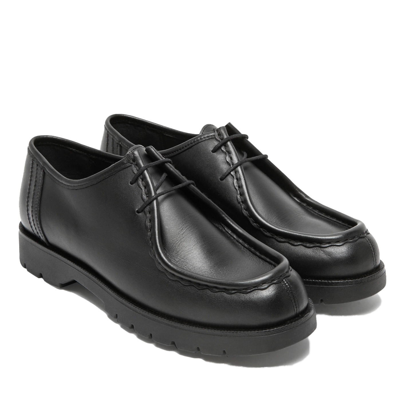 A pair of black, cowhide leather shoes with a serrated hem and fancy stitching, featuring a durable rubber outsole and tonal wax laces.