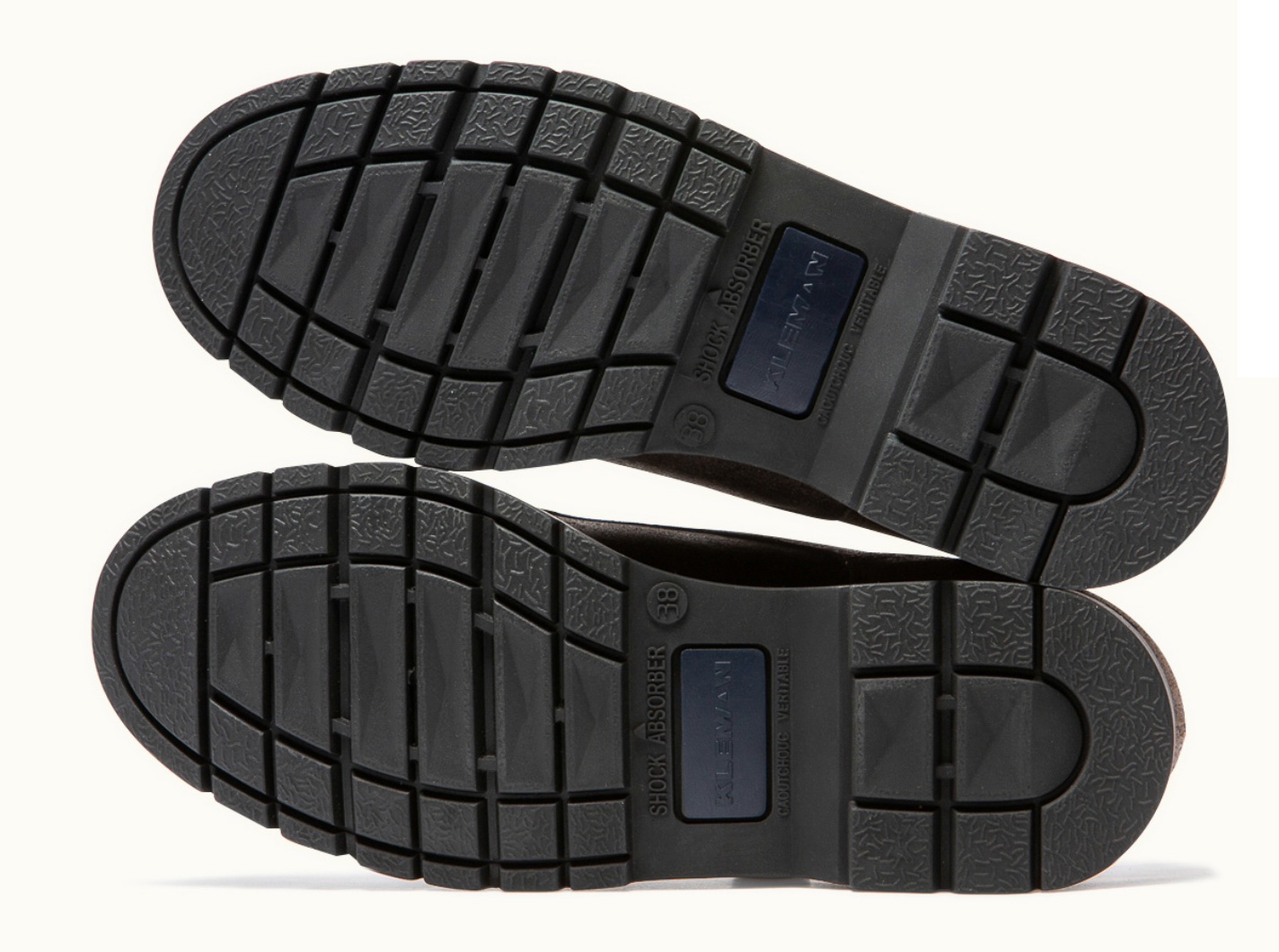 A pair of black, cowhide leather shoes with a serrated hem and fancy stitching, featuring a durable rubber outsole and tonal wax laces.