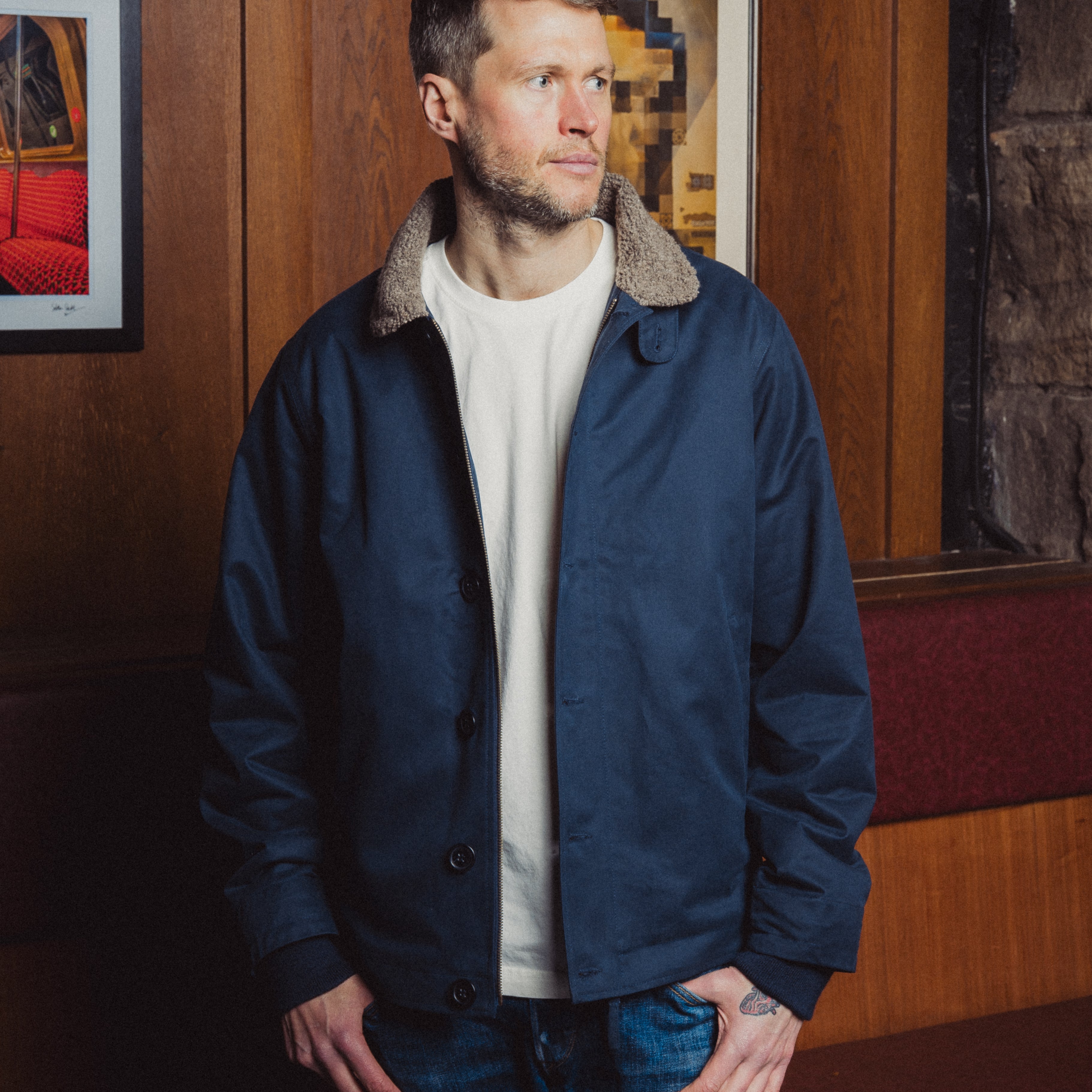 Man wearing a navy blue jacket with fur collar in an indoor setting
