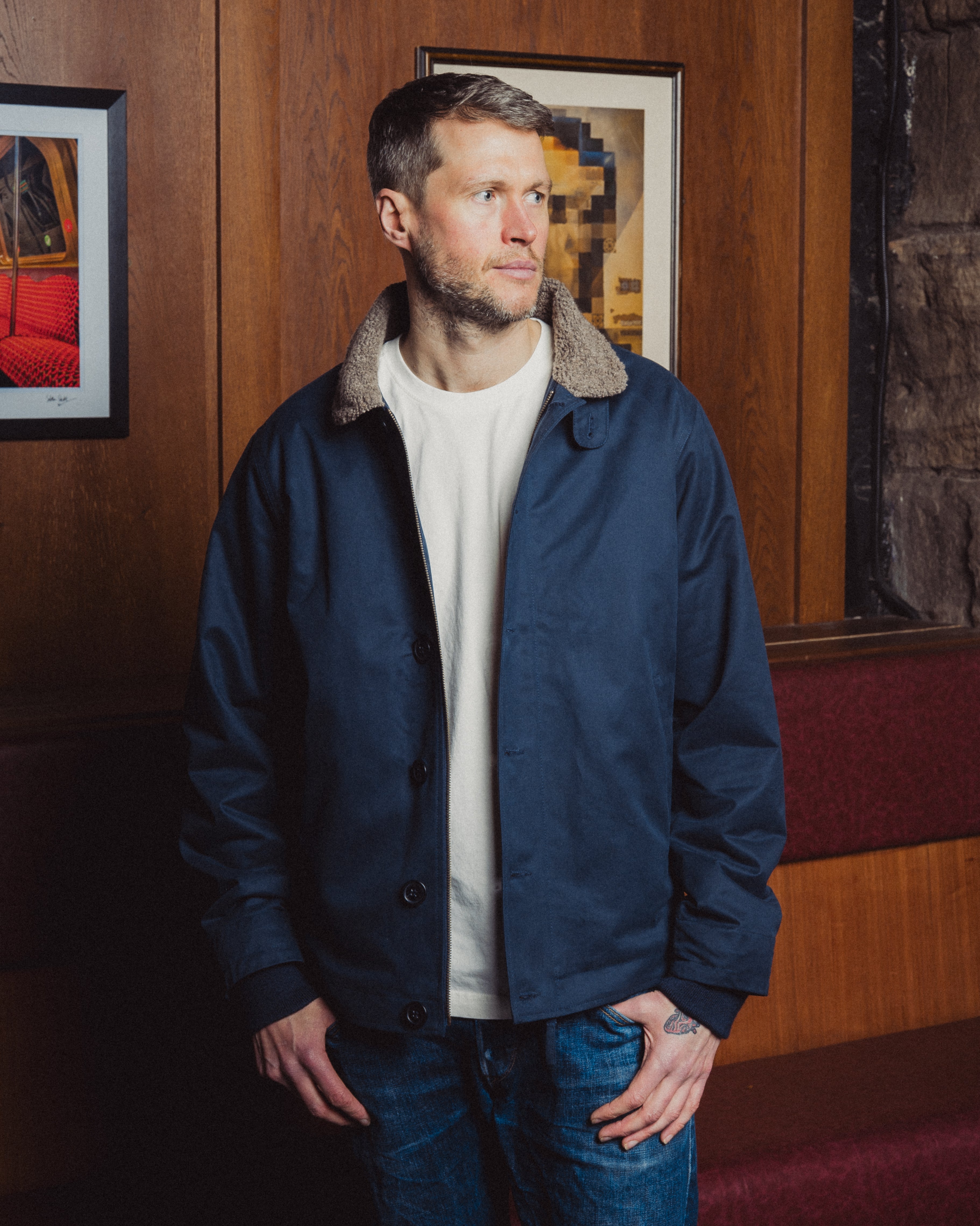 Man wearing a navy blue jacket with fur collar in an indoor setting