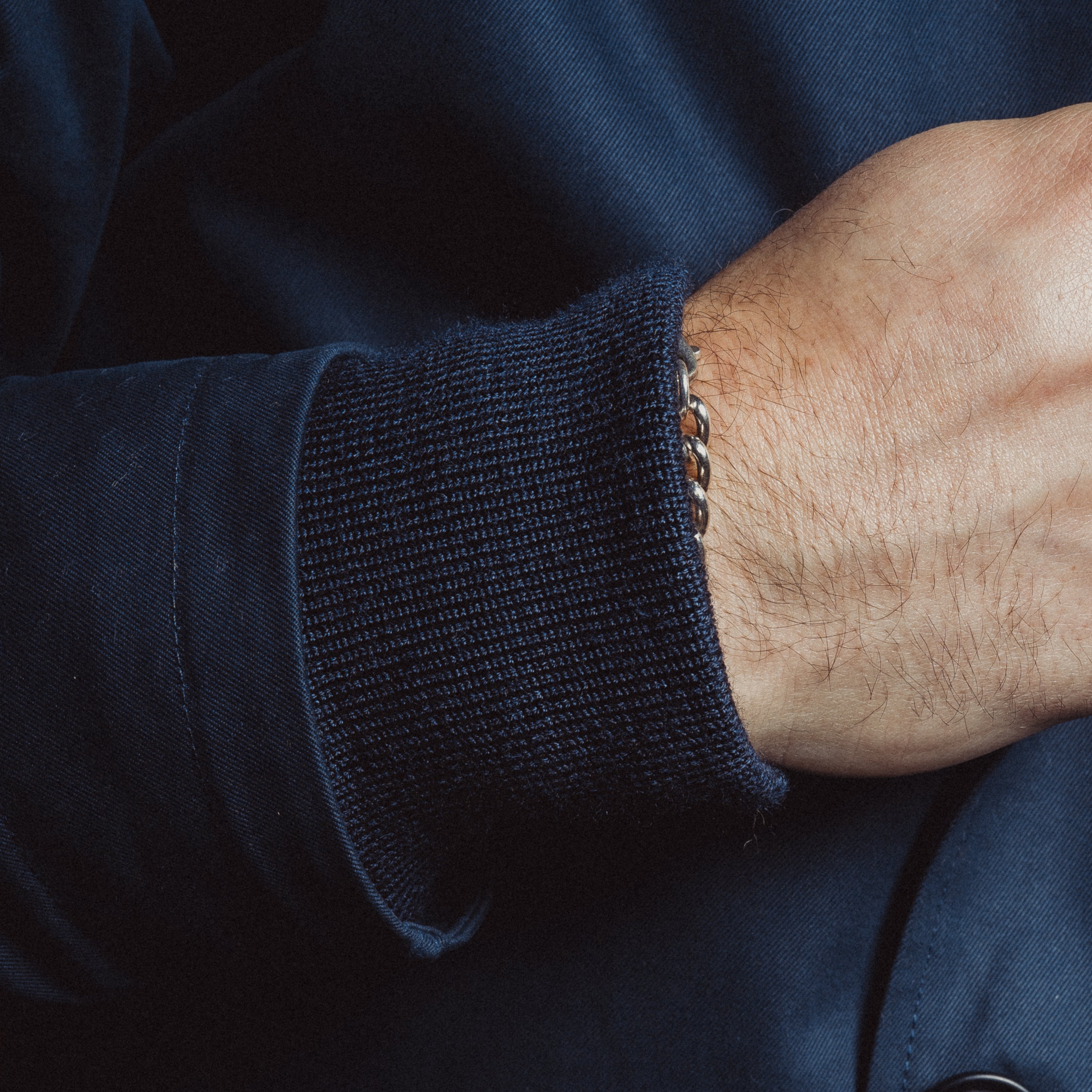 Close-up of a person wearing a navy blue jacket with a buttoned cuff.