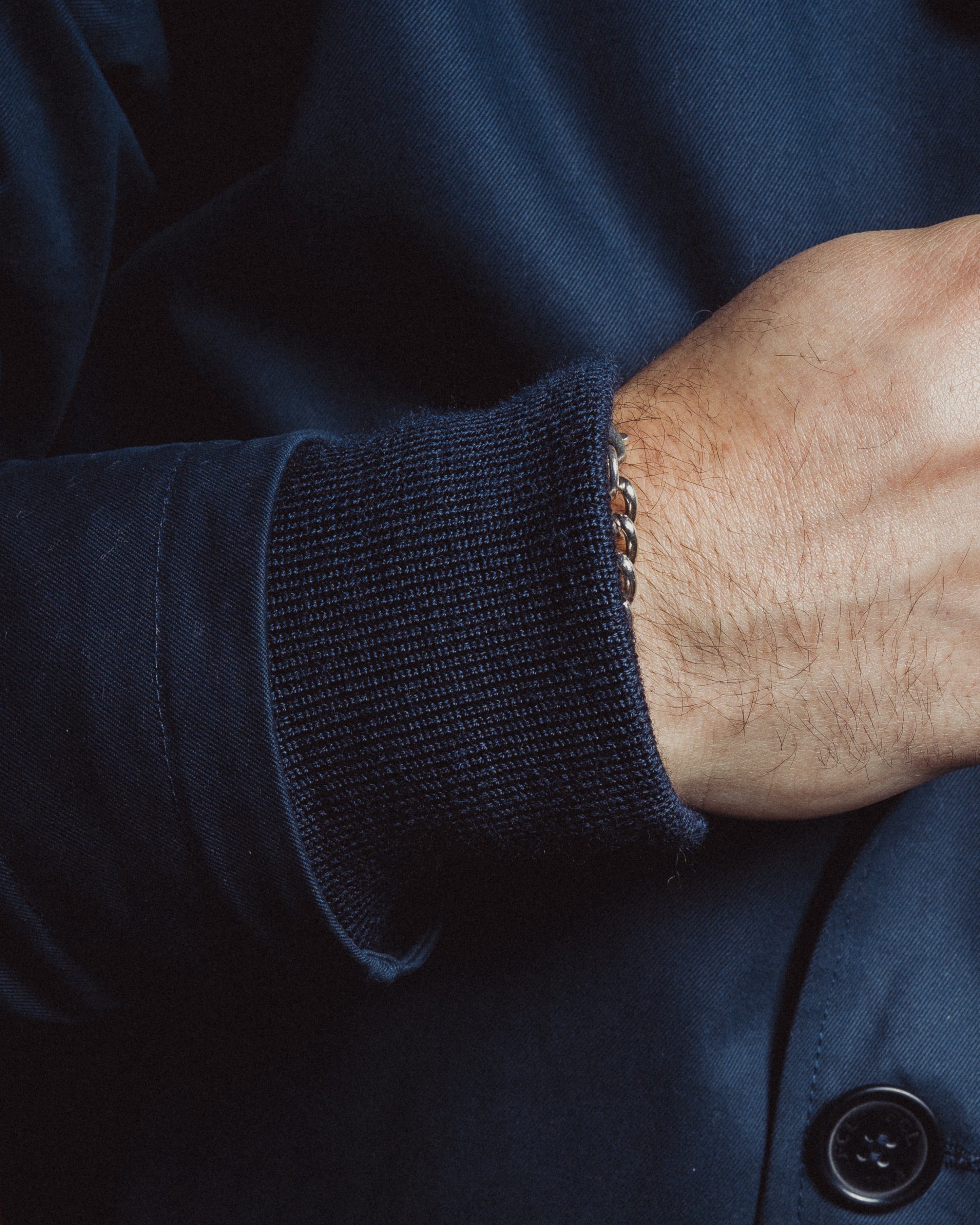 Close-up of a person wearing a navy blue jacket with a buttoned cuff.