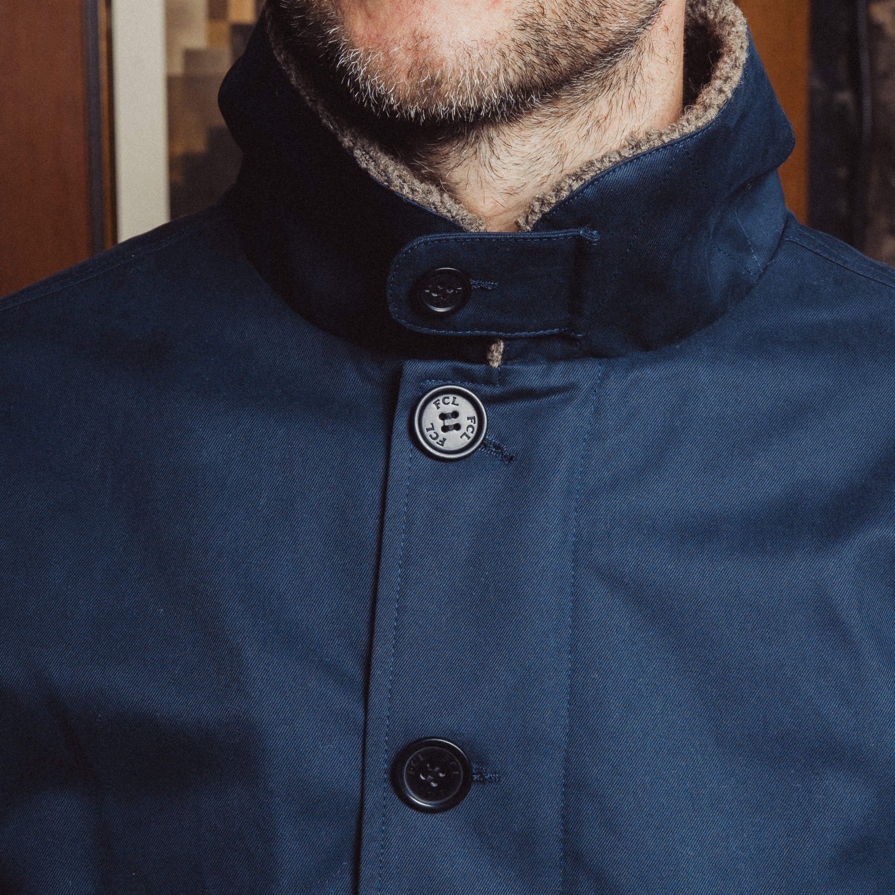 Close-up of a blue coat with buttons, focusing on the collar and buttons.