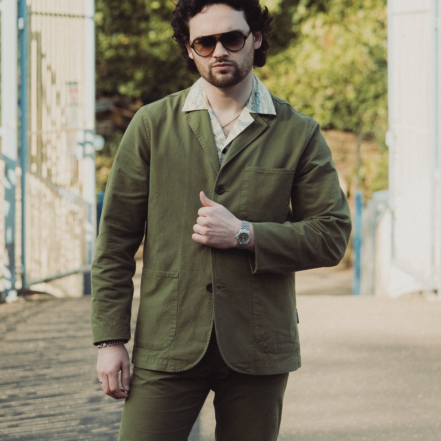 Man wearing a green jacket and sunglasses outdoors