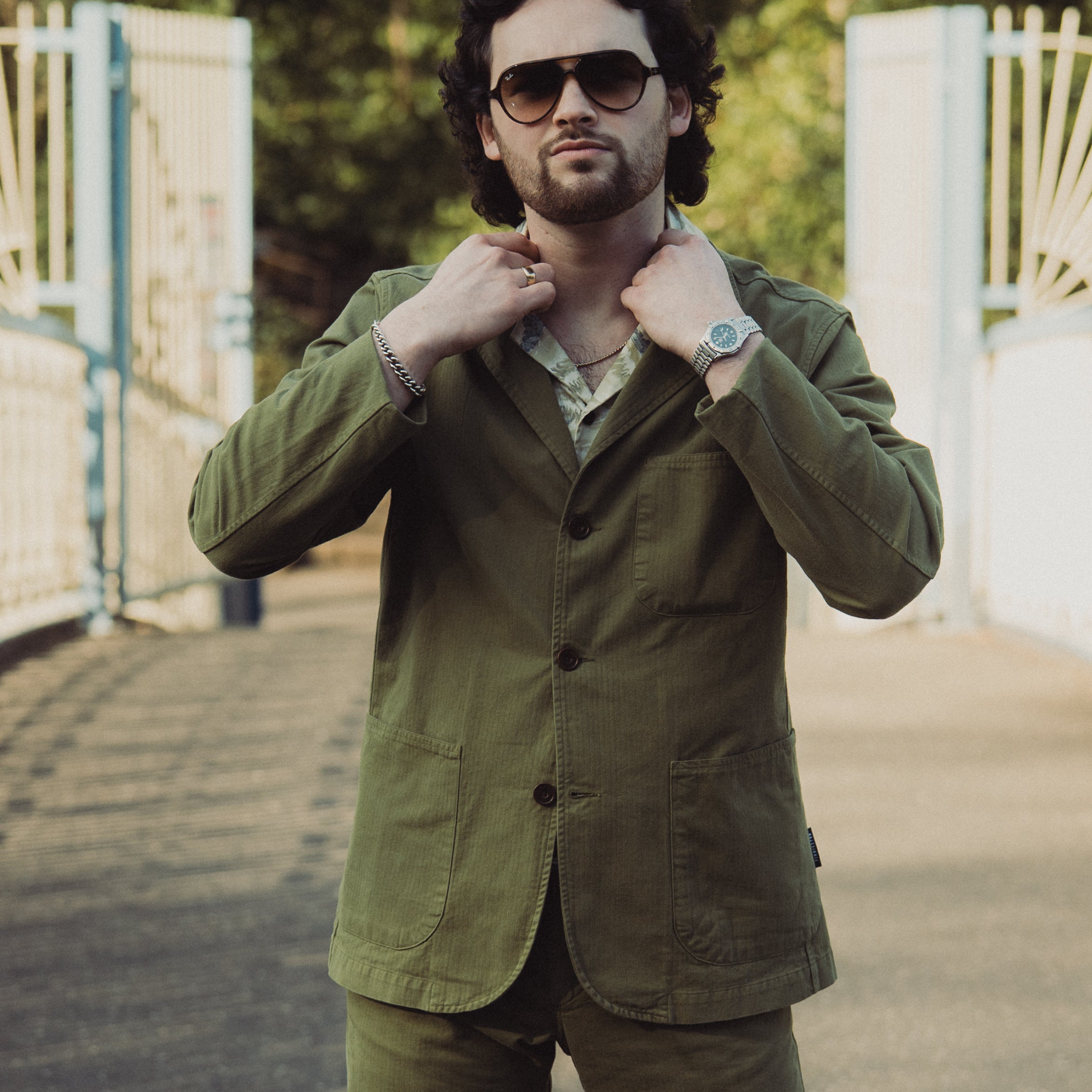 Man wearing a green jacket and sunglasses outdoors