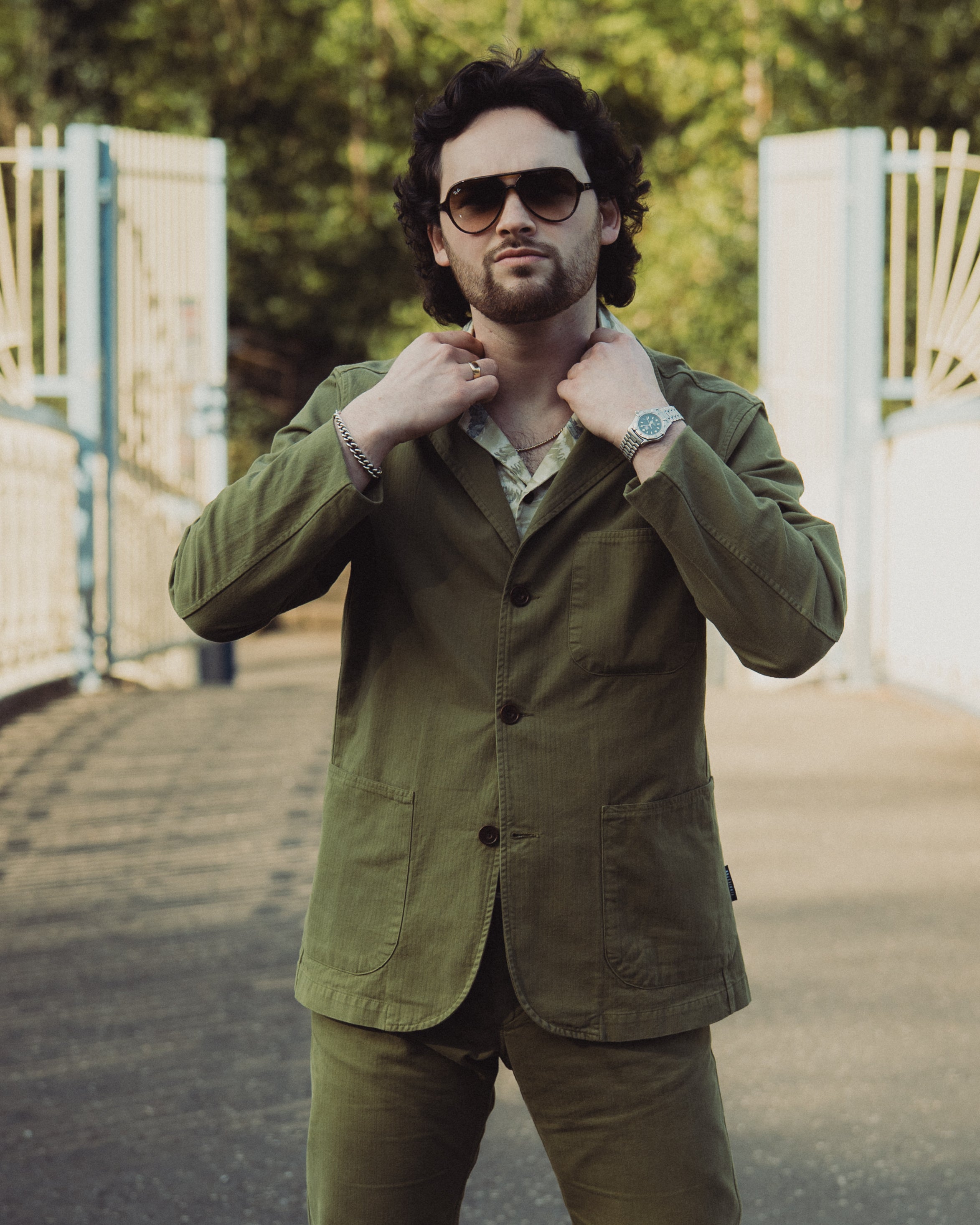 Man wearing a green jacket and sunglasses outdoors
