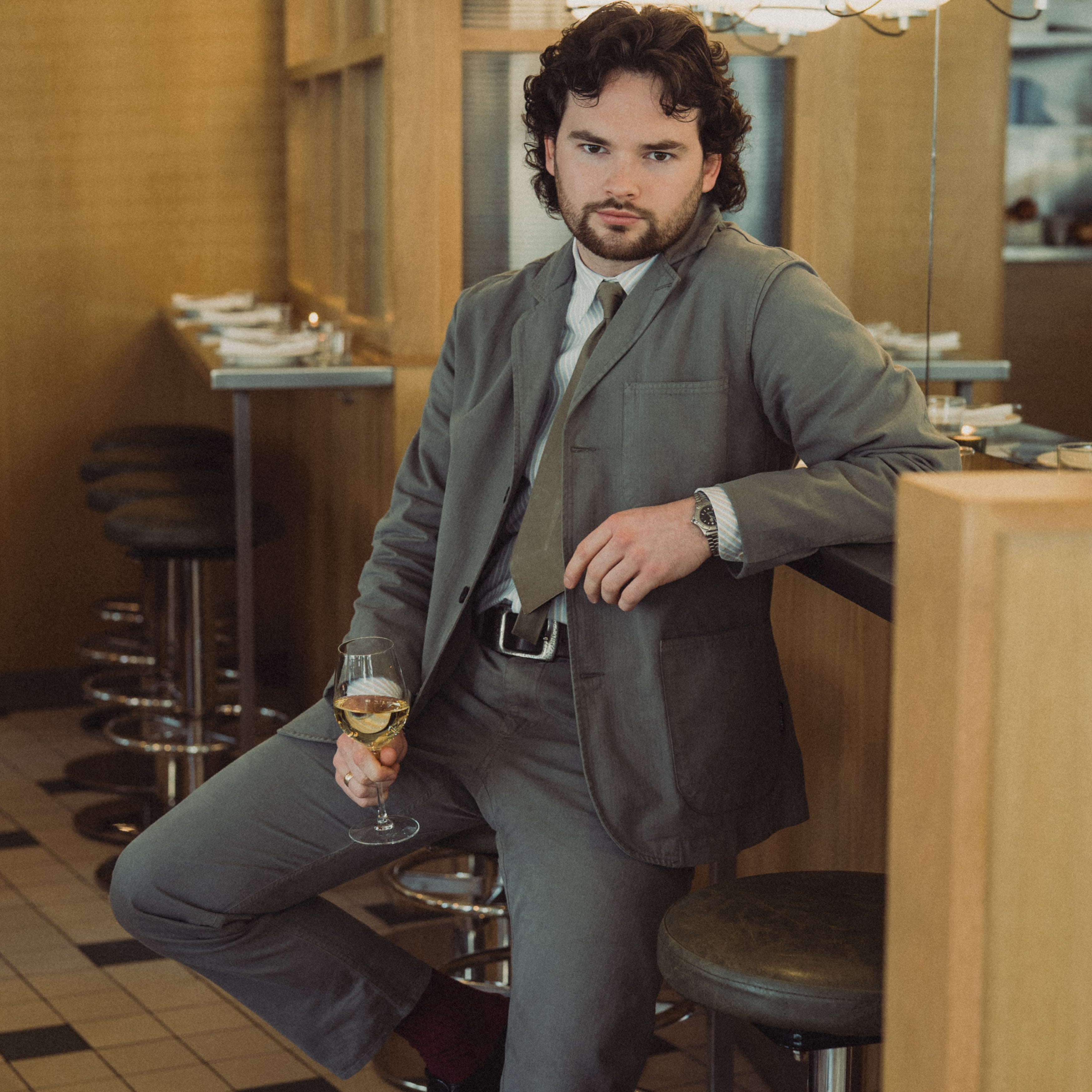Man in a suit holding a glass of wine in a restaurant setting