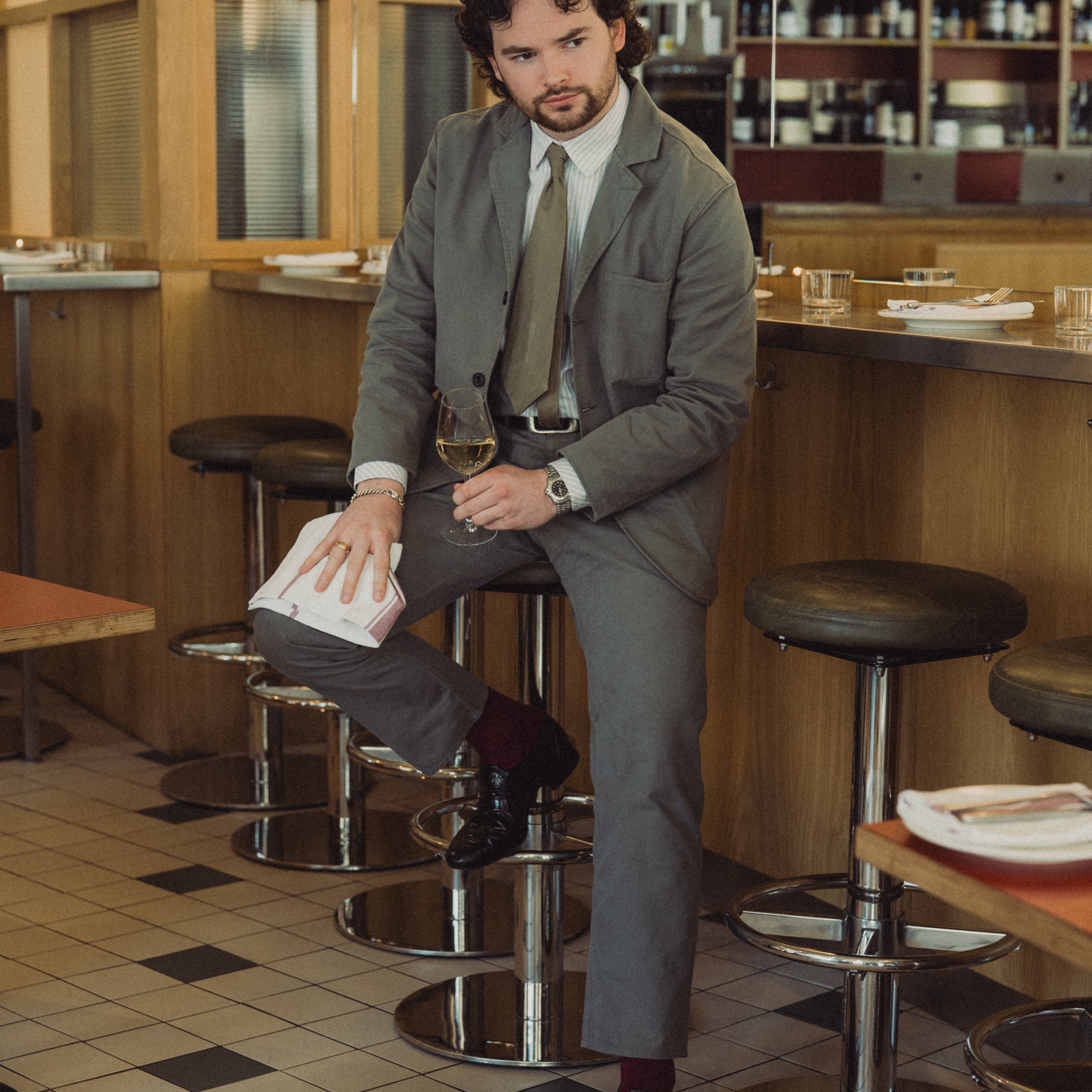 Man in a suit sitting on a bar stool in a restaurant.