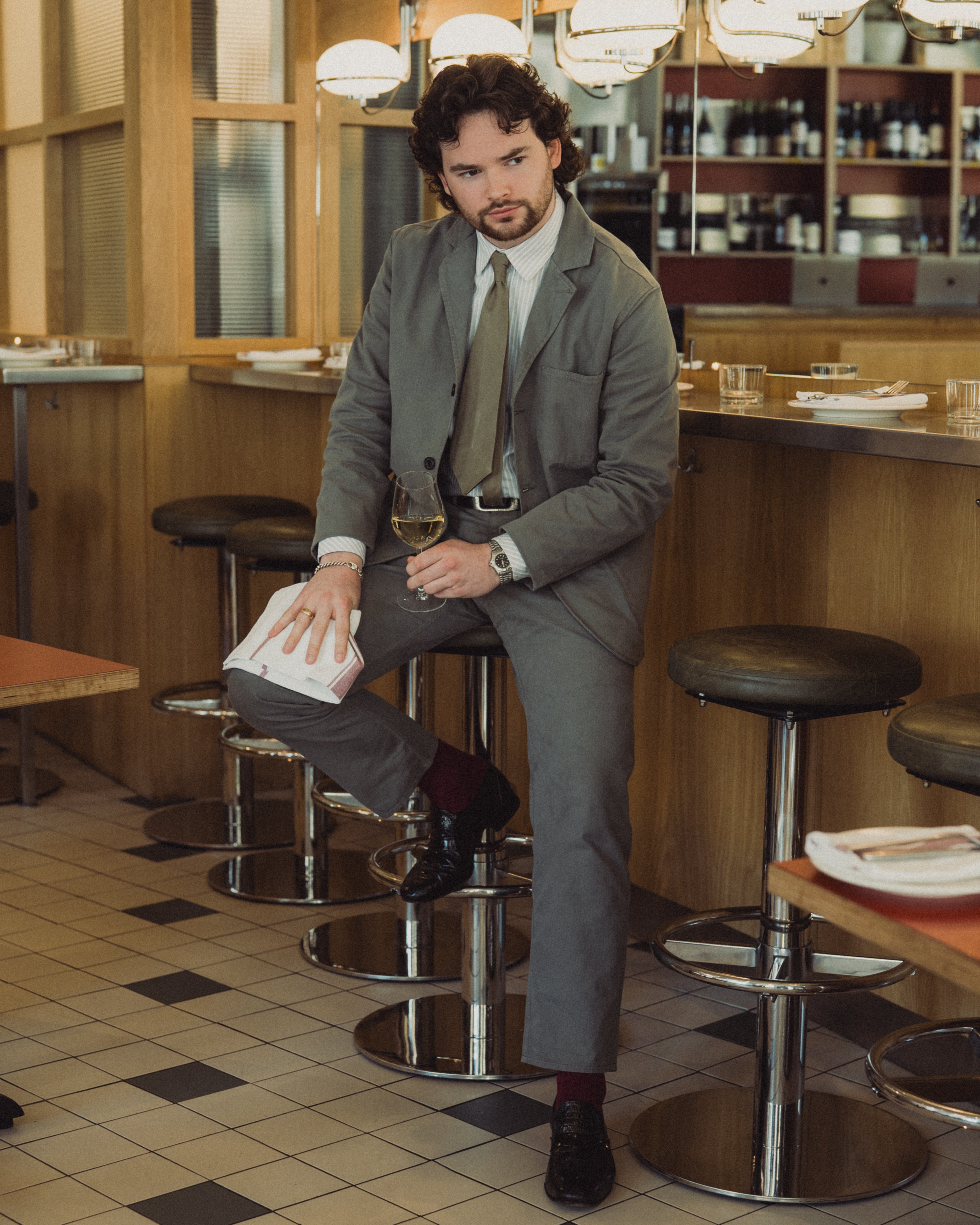 Man in a suit sitting on a bar stool in a restaurant.