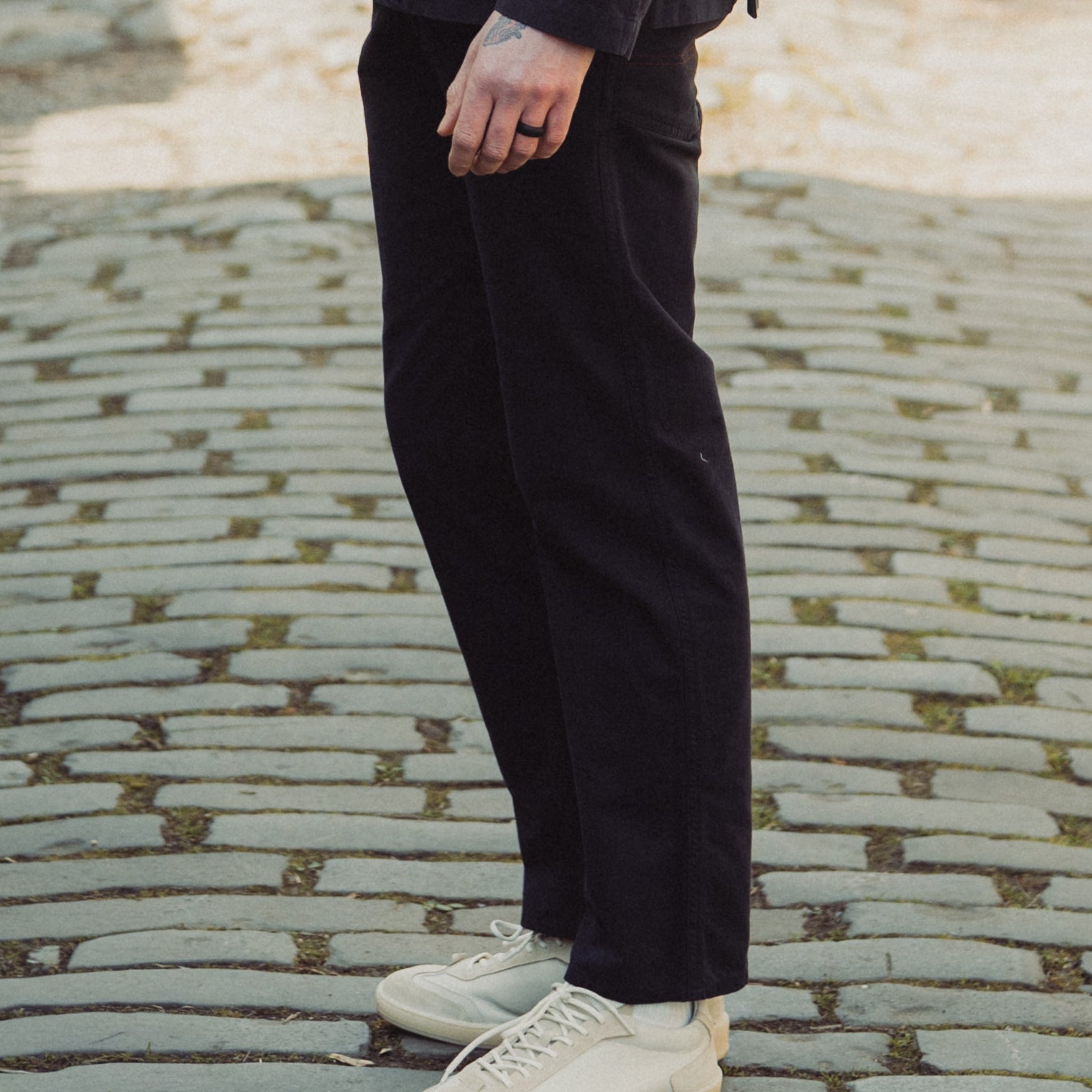 Man in a dark suit and sunglasses standing on a cobblestone street.