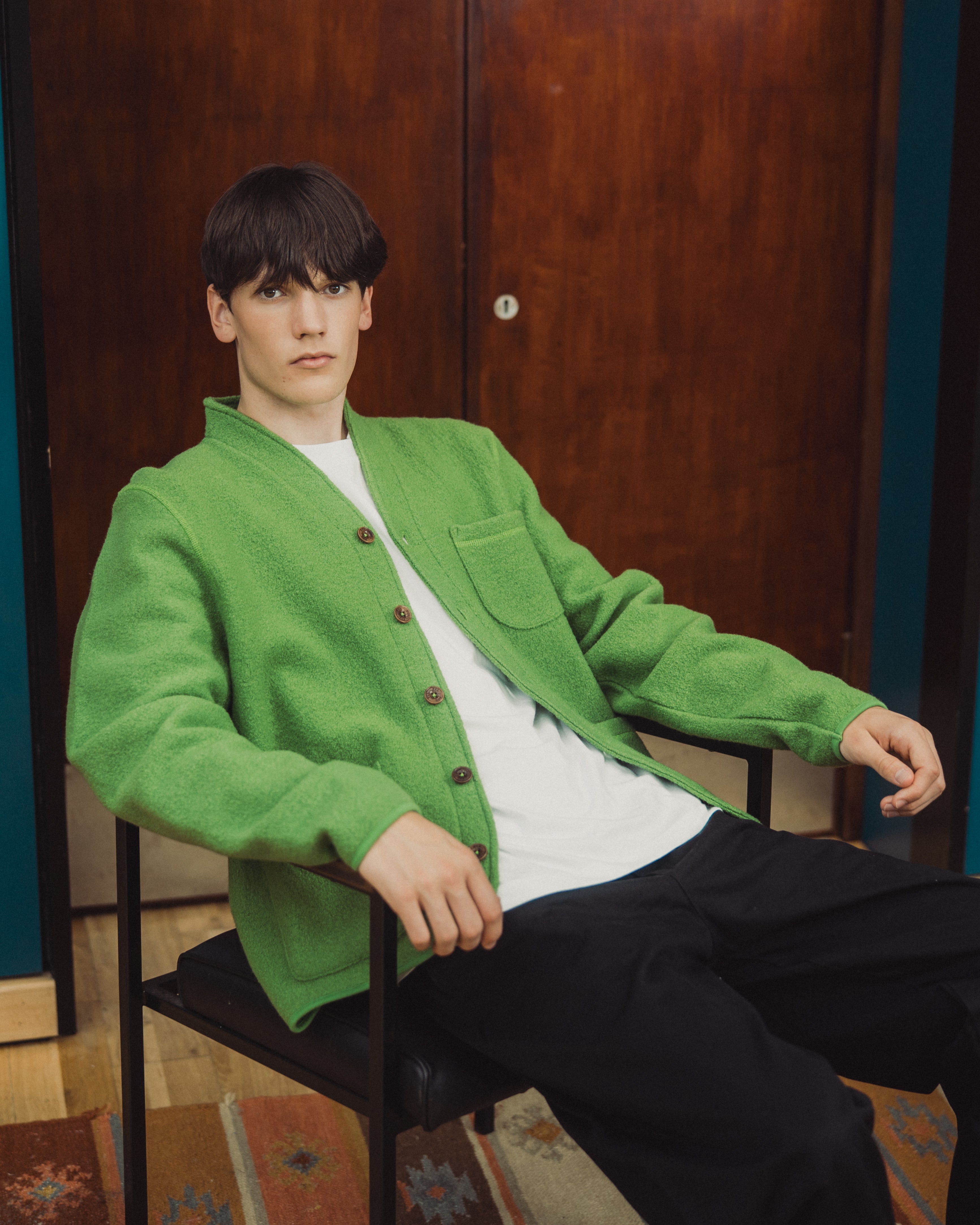 man with green wool cardigan on, with white tee shirt underneath