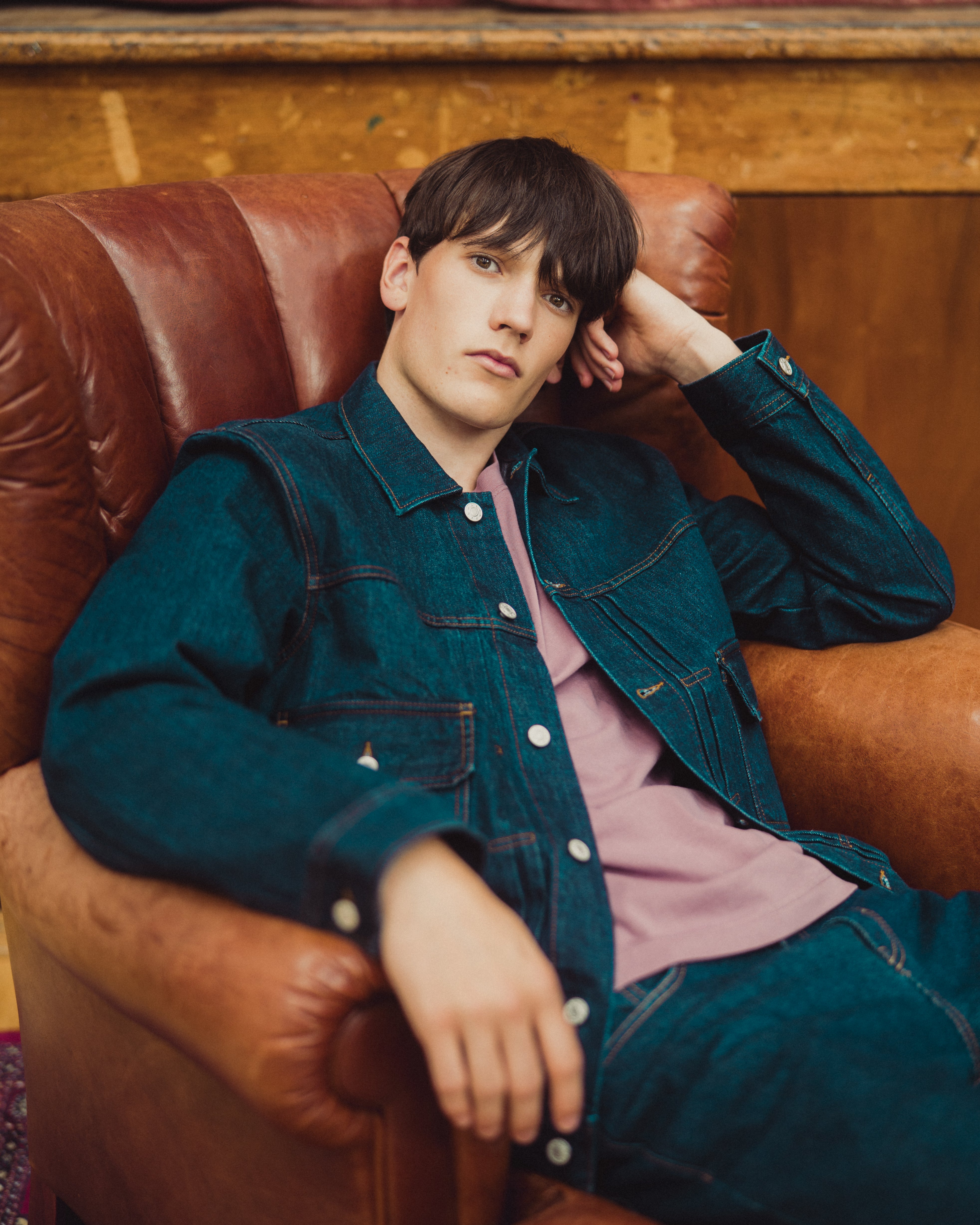 man in denim jacket on leather chair