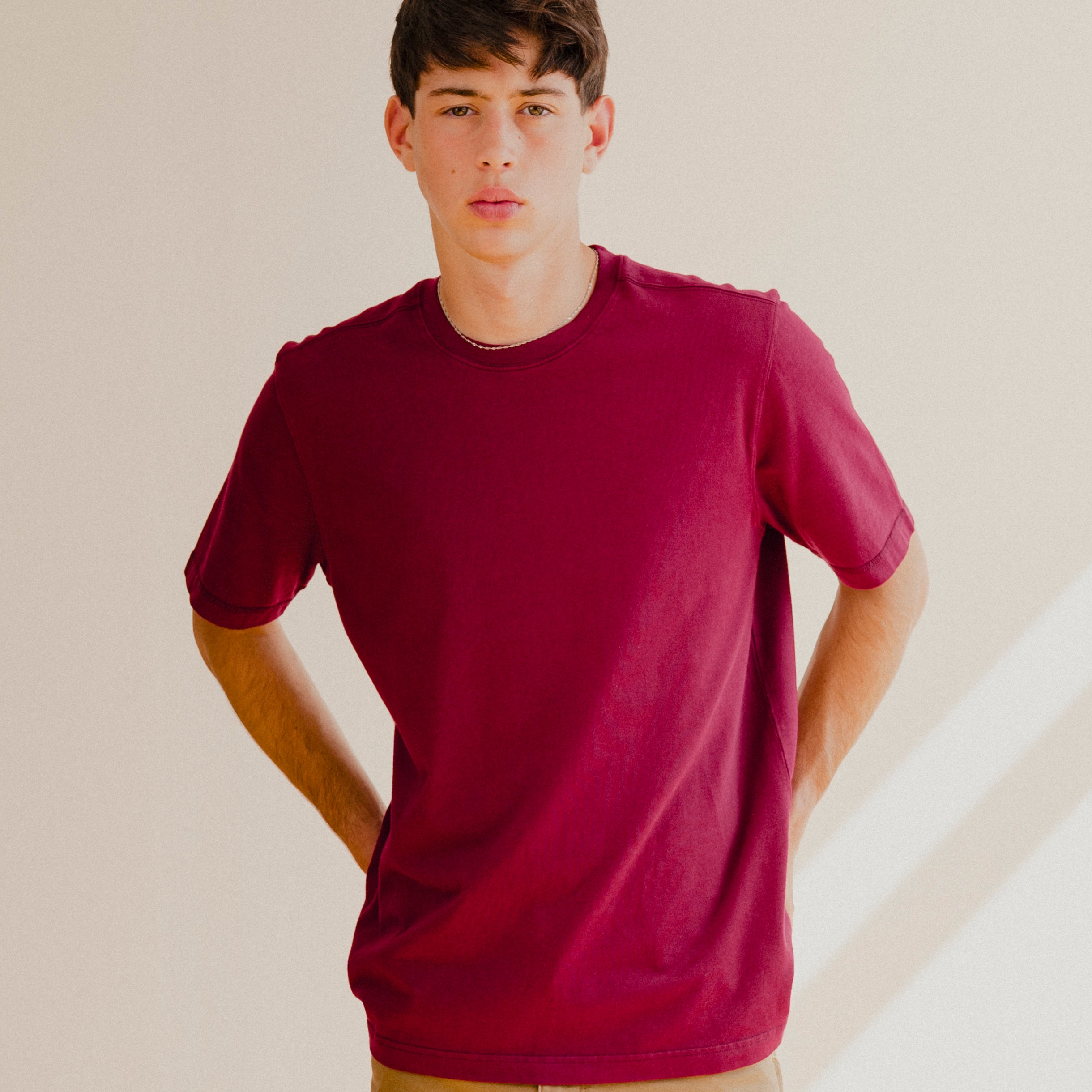Man wearing a maroon red t-shirt against a plain background