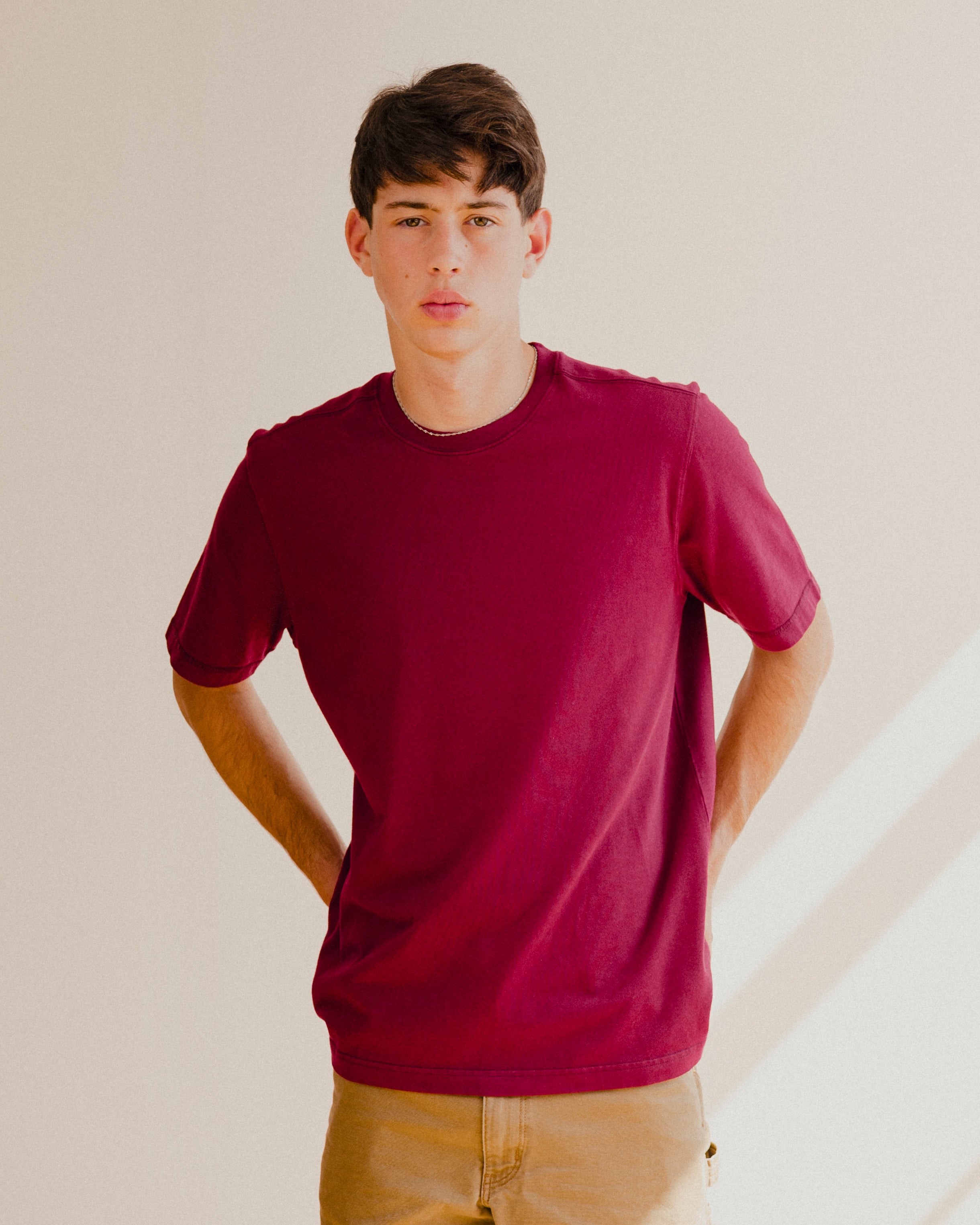 Man wearing a maroon red t-shirt against a plain background