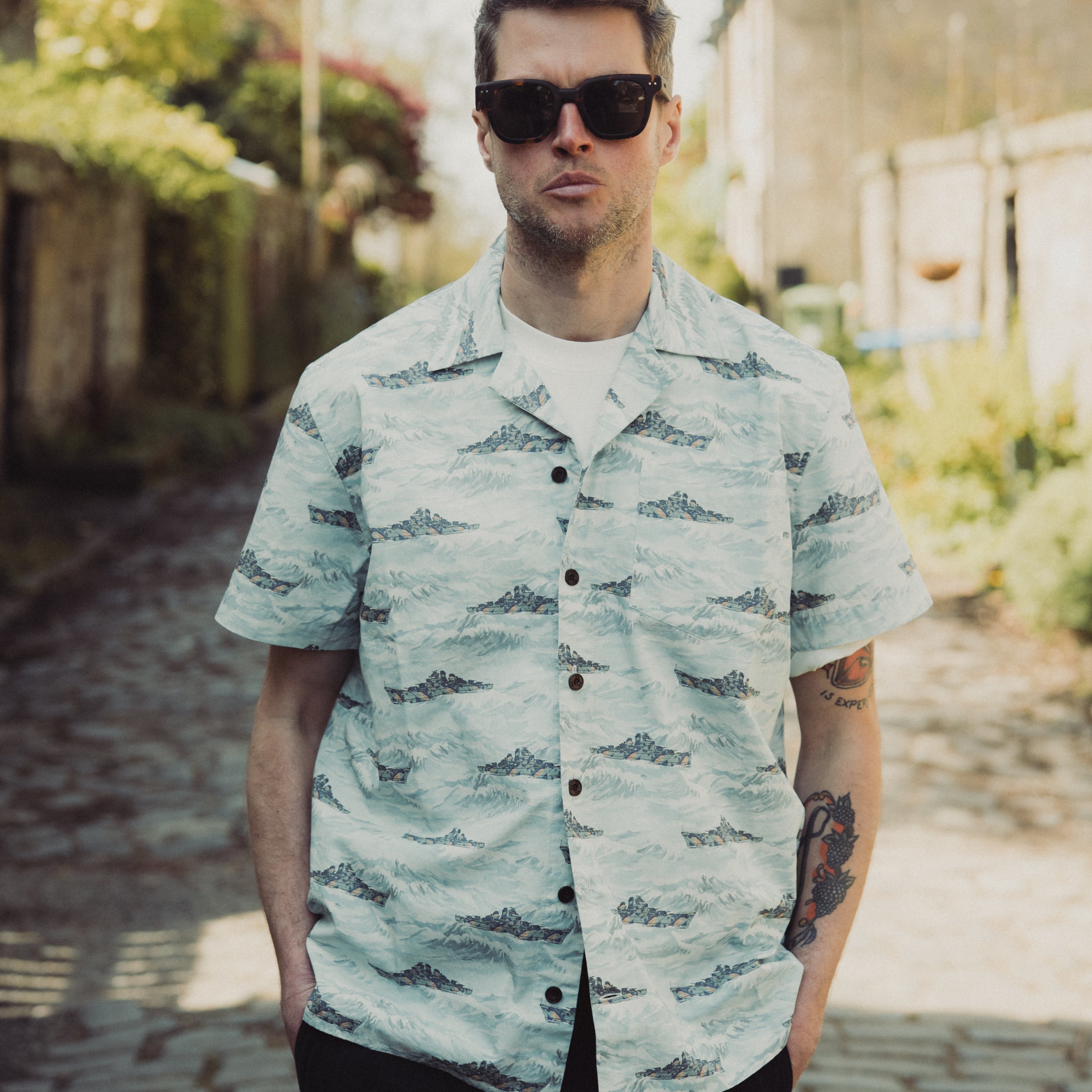 Man wearing a patterned shirt and sunglasses outdoors