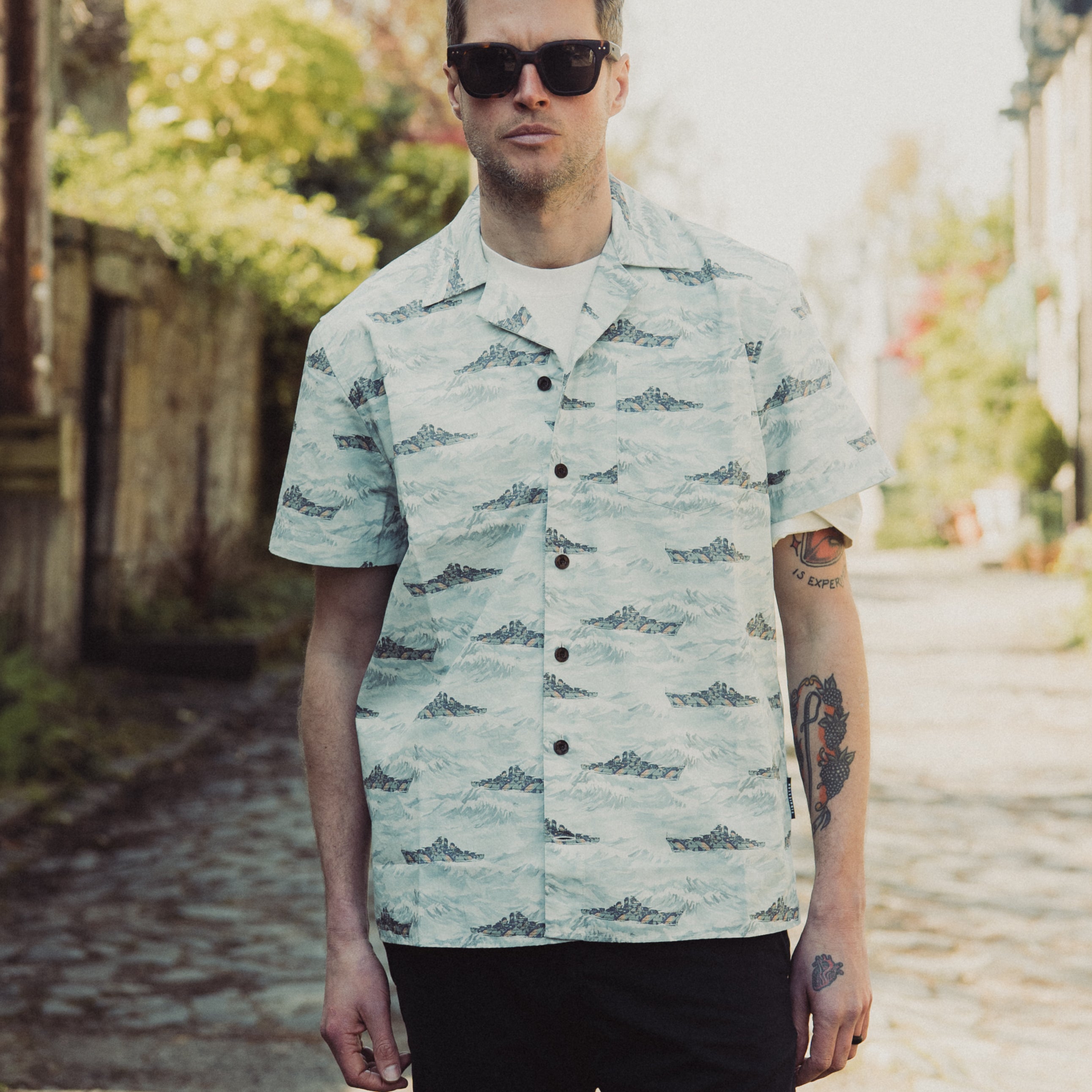 Man wearing a patterned shirt and sunglasses outdoors