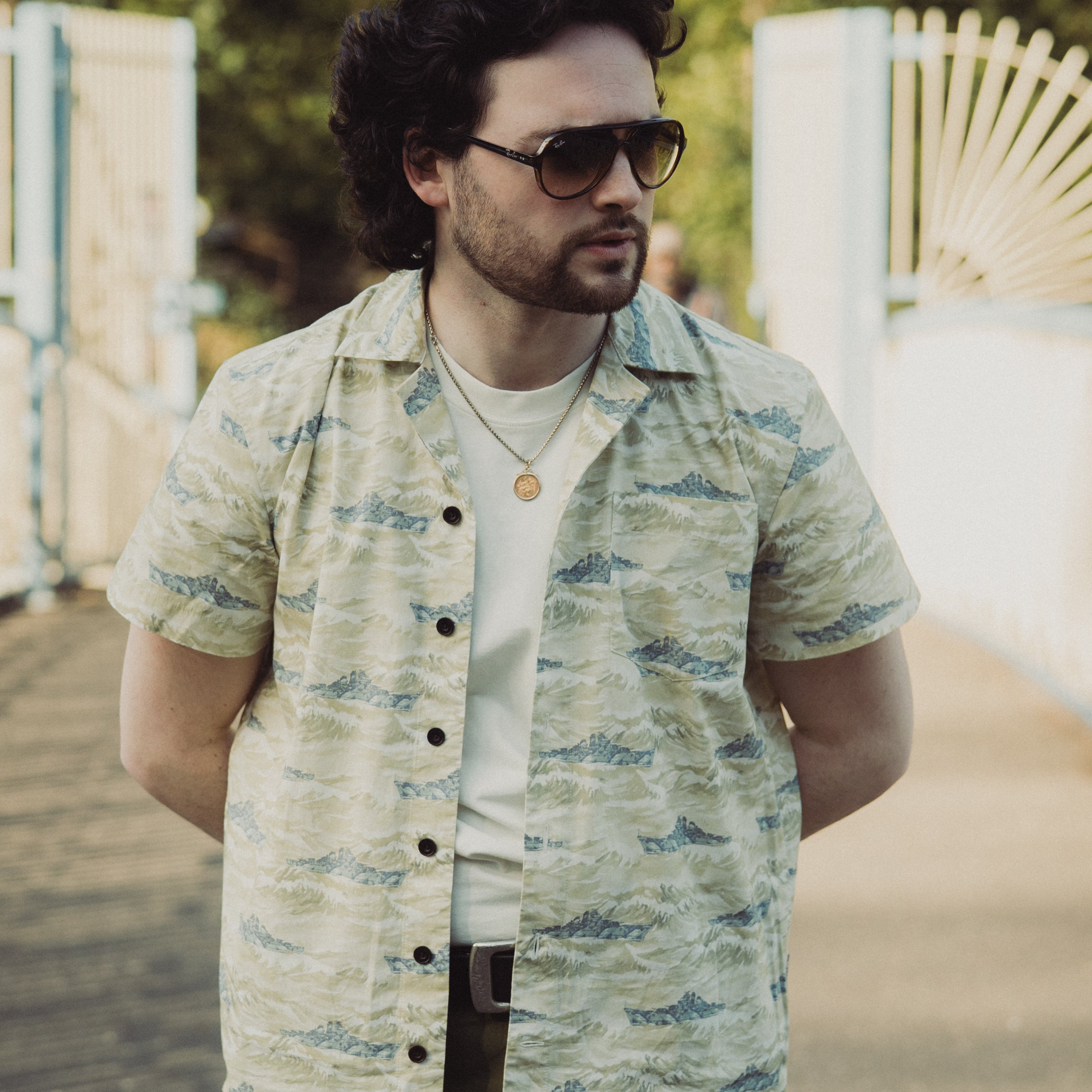Man wearing a patterned shirt and sunglasses outdoors