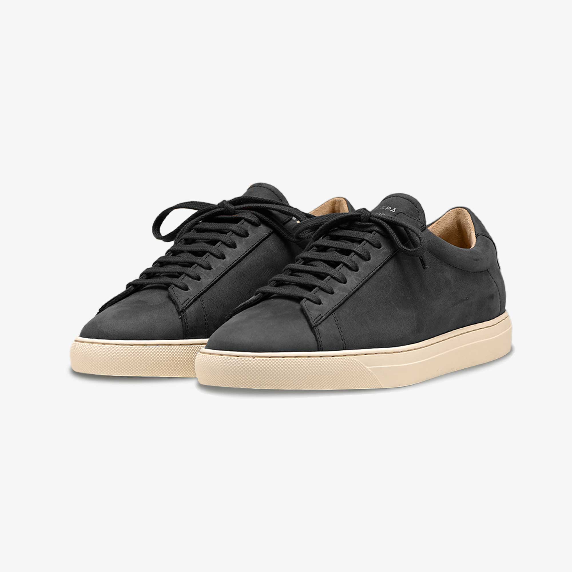 Pair of black sneakers with beige soles on a white background