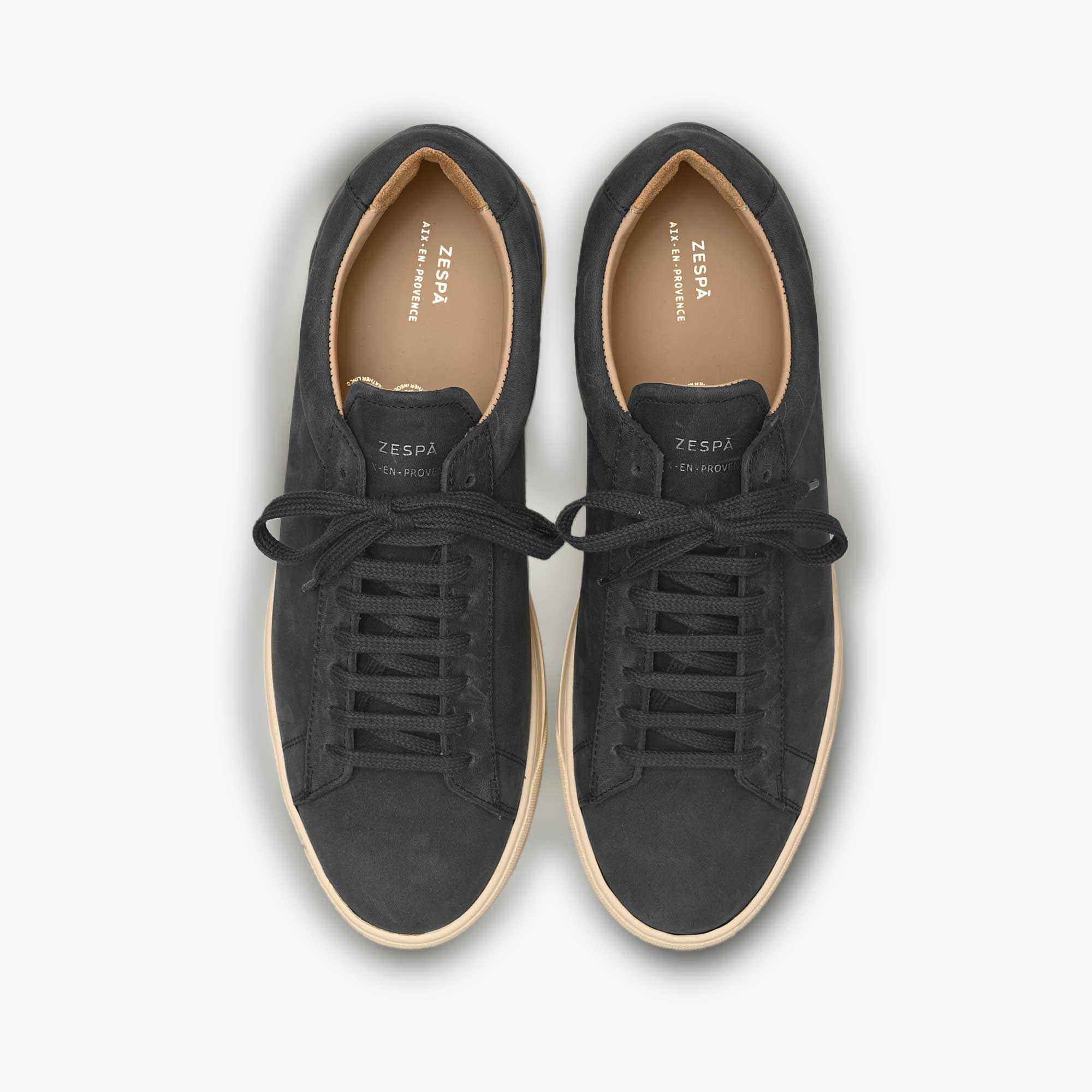 Pair of black Zespa sneakers with white soles on a light gray background
