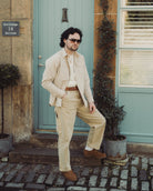 Man in beige suit standing in front of a teal door