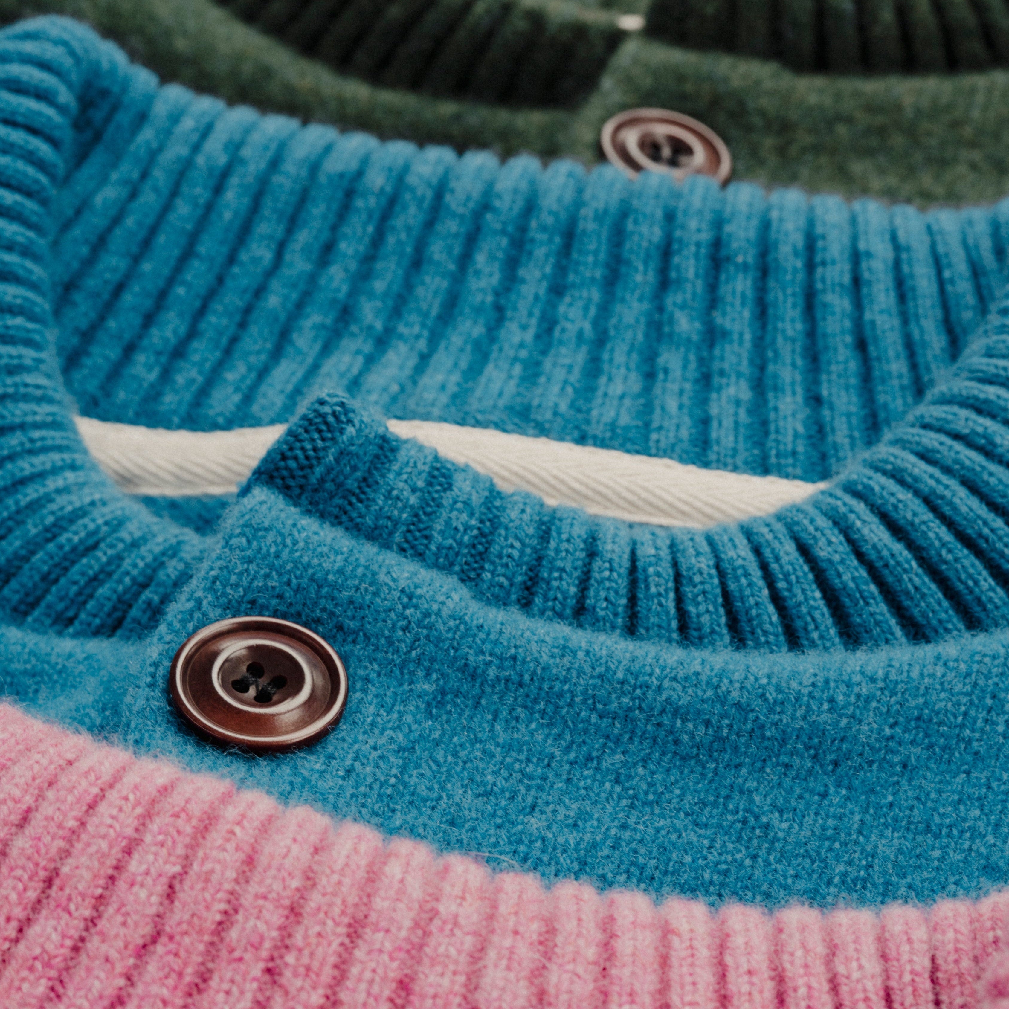 Close-up of a blue and pink sweater with a button detail.