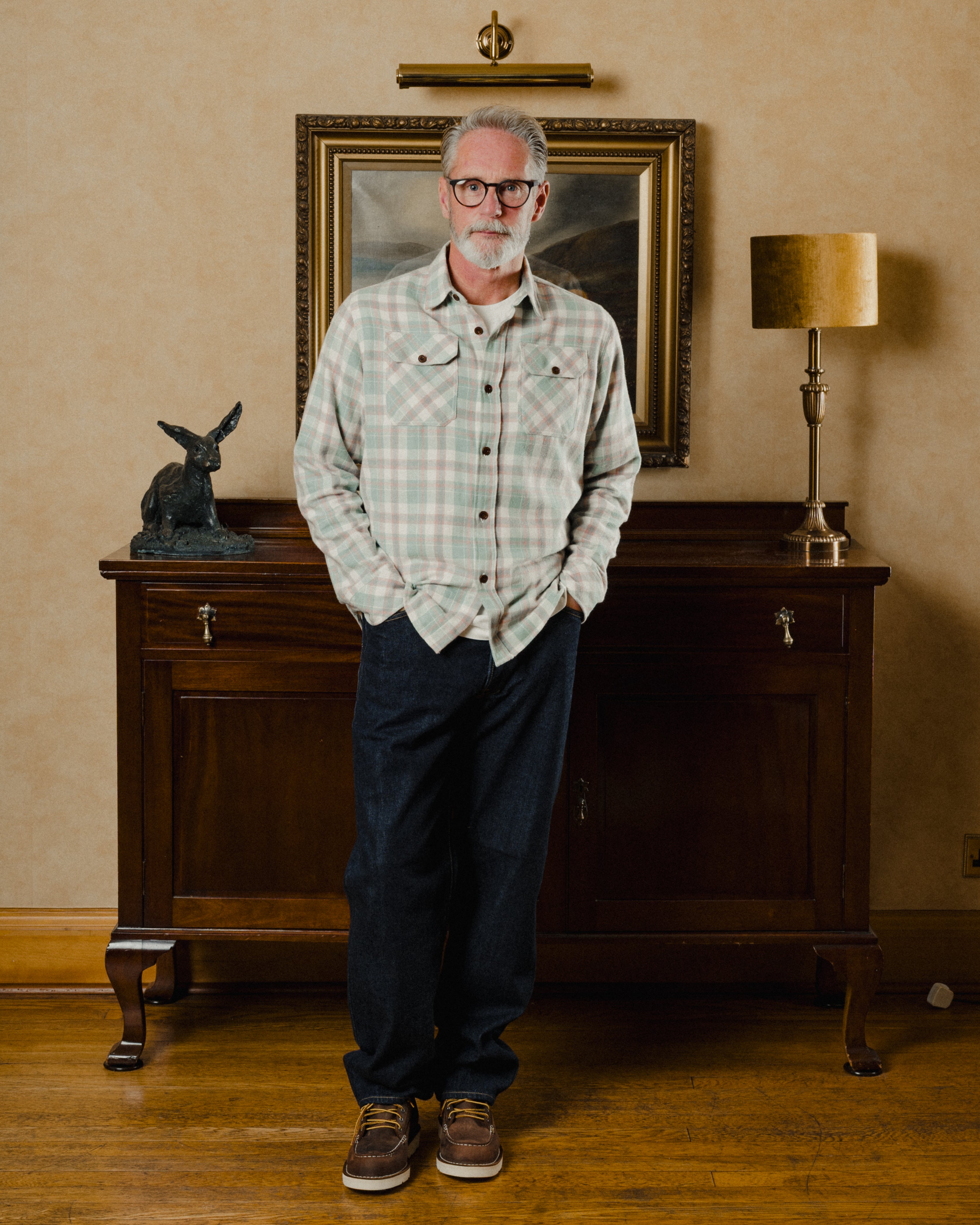 Man standing in a room with wooden furniture and decorative items