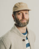 Man wearing a beige cap and light-colored jacket with a plain background